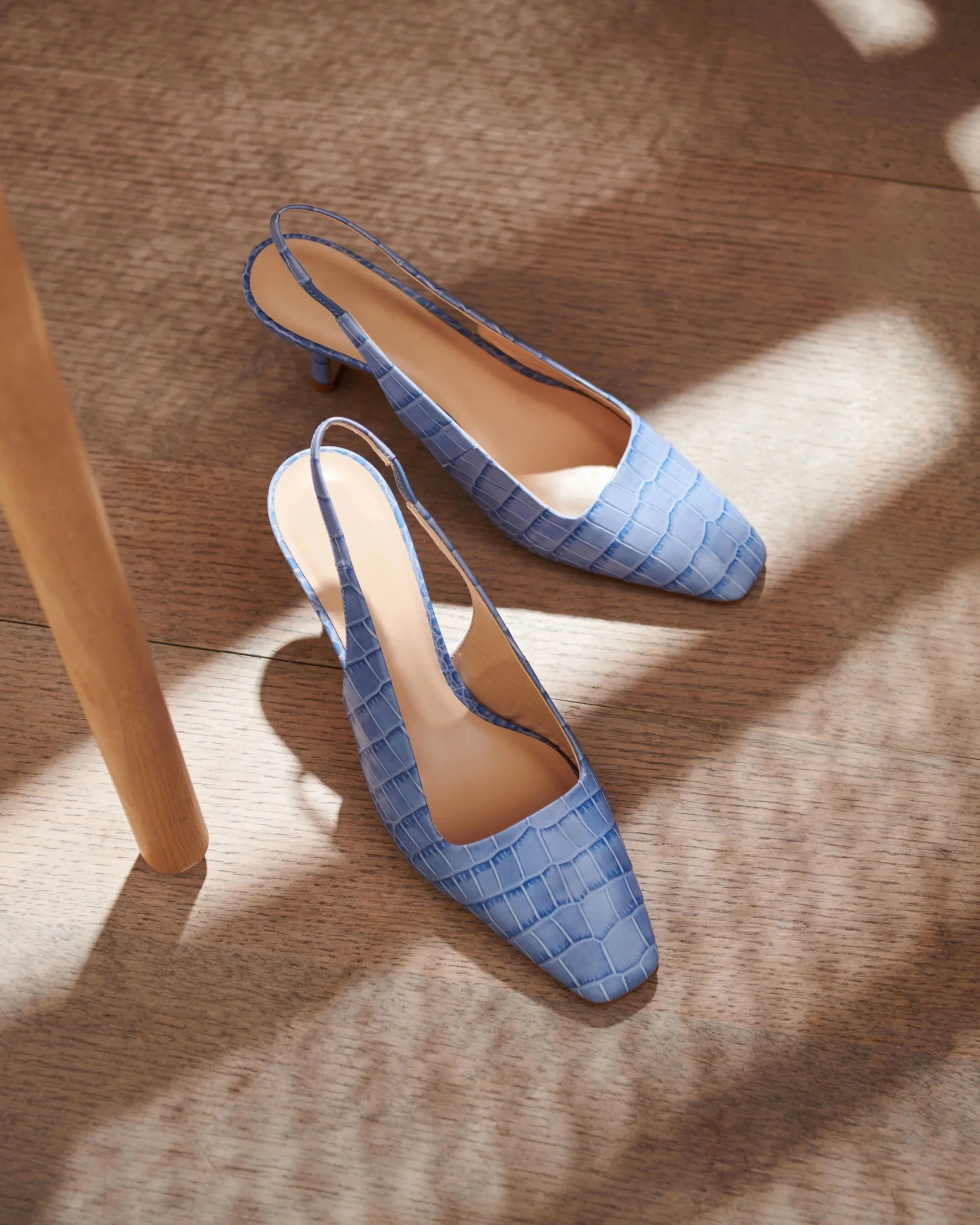 women's blue snake pattern slingback shoes on wood floor set in shadow of a sunlit chair