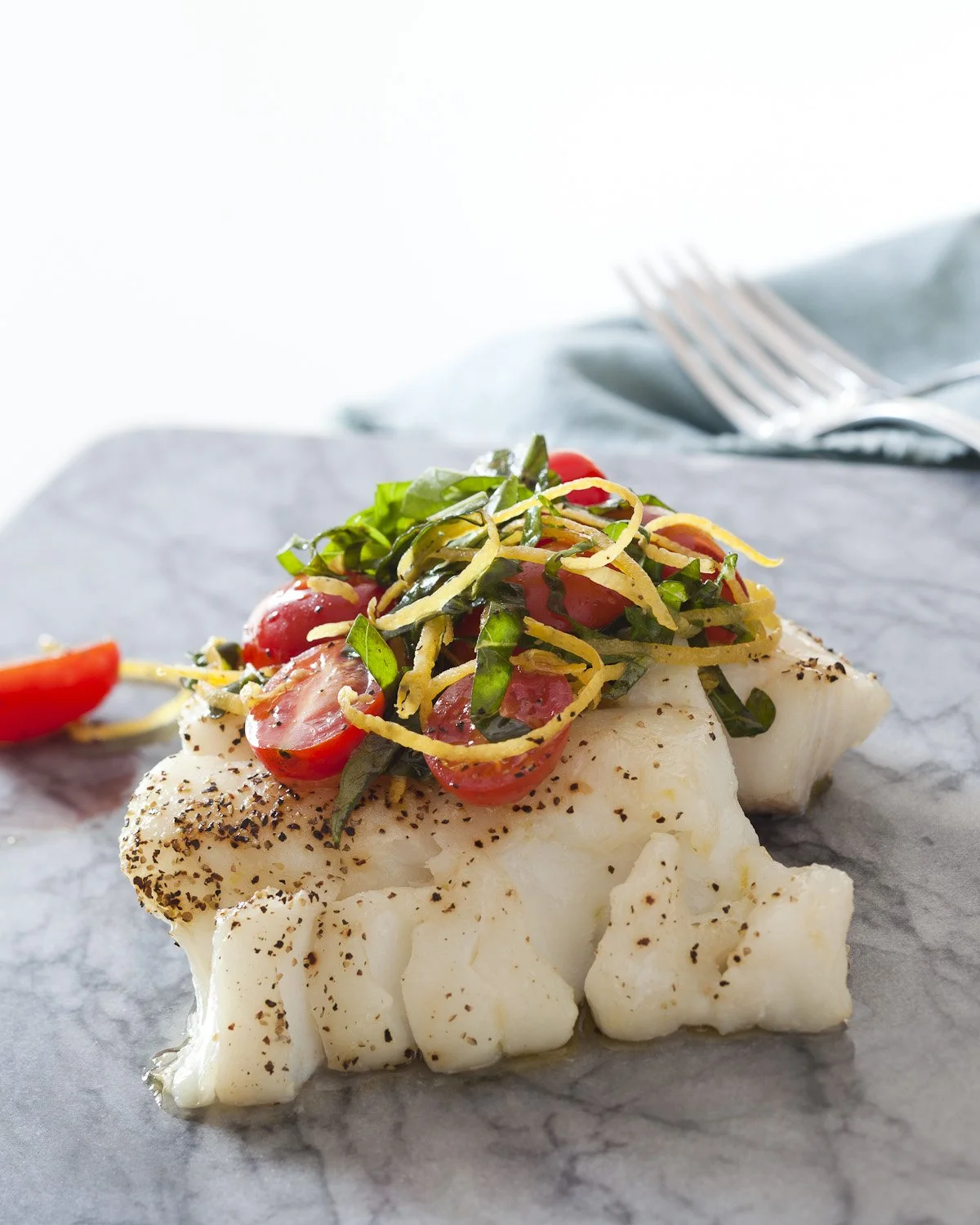 plated cod serving with tomato, lemon and basil topping