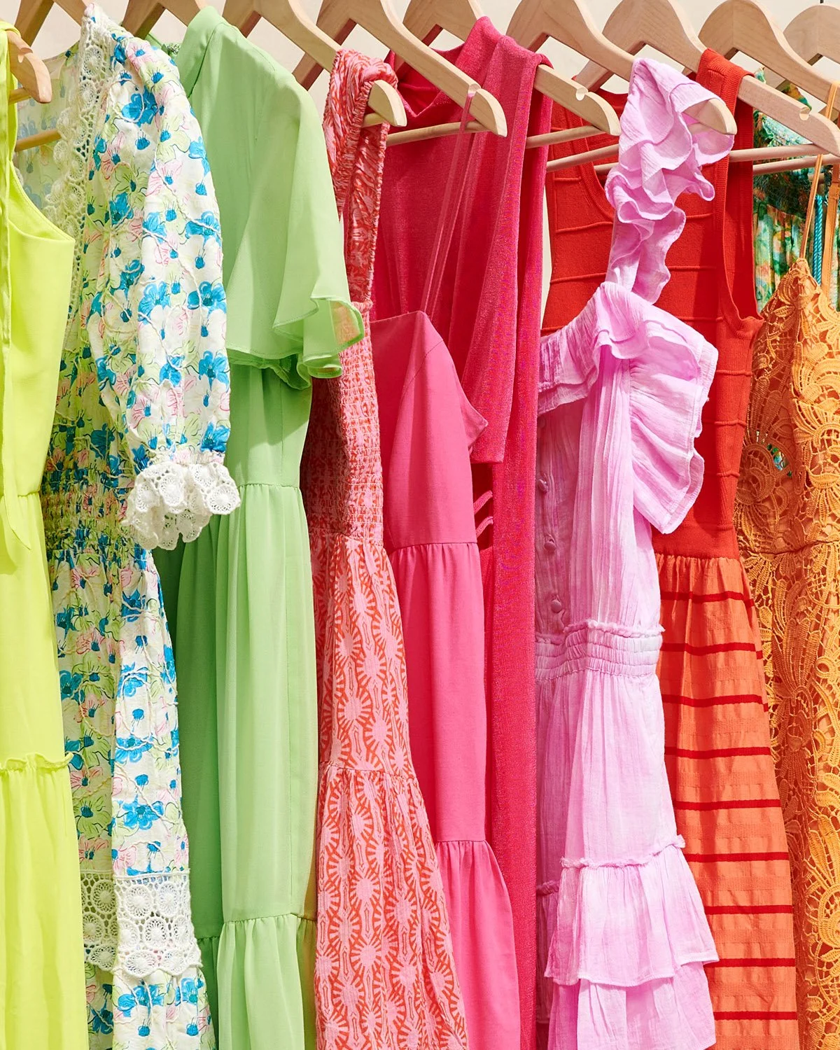 close up textures and patterns of bright colorful dresses on hangers 