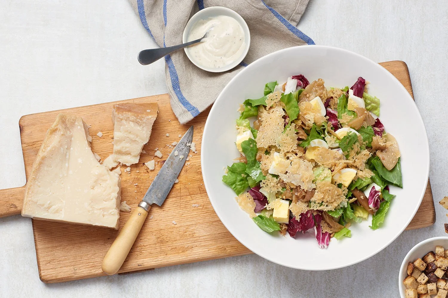 caesar salad on cutting board with parmesan cheese and knife
