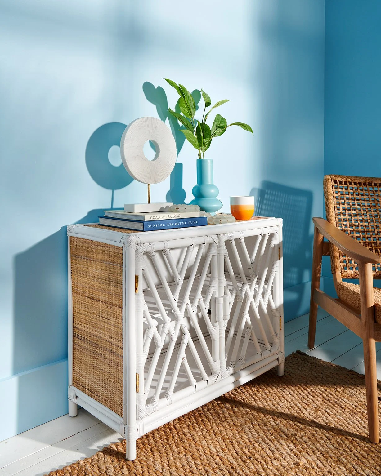 white bamboo and weave furniture console set in room with blue walls and strong sunlight pattern