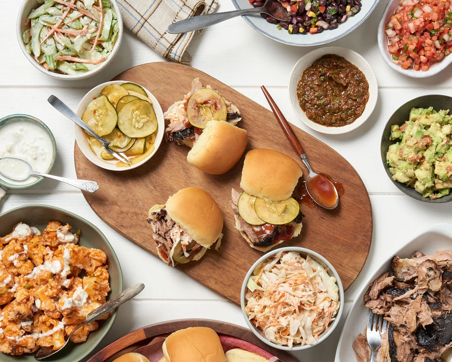 overhead view of brisket slider tray with pickles, coleslaw and other side dishes
