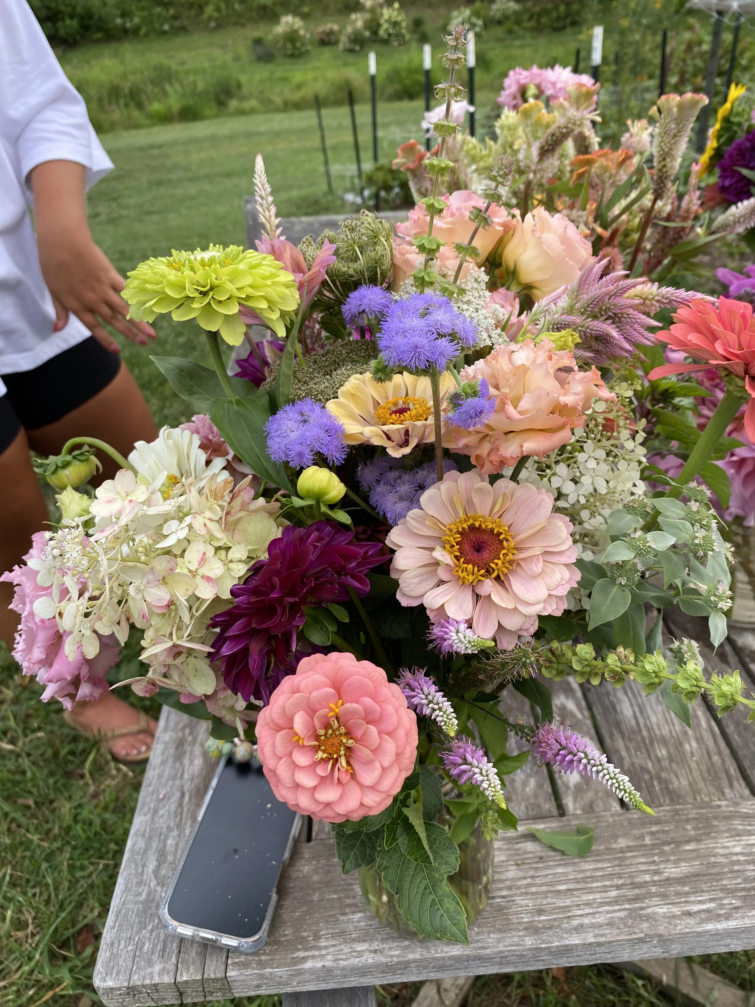 Colorful bouquet of various flowers on a wooden table in an outdoor garden setting.