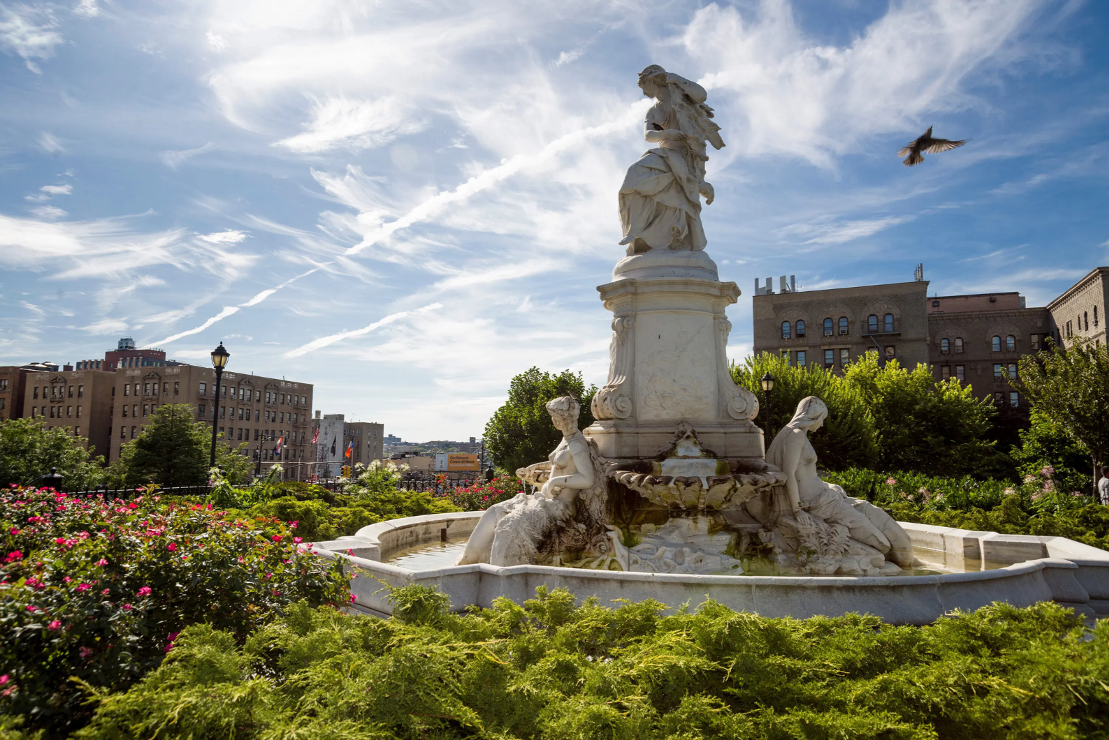 The marble Lorelei Fountain surrounded by greenery and flowers in the Bronx's Joyce Kilmer park facing East 161st Street photographed by Adama Pape.