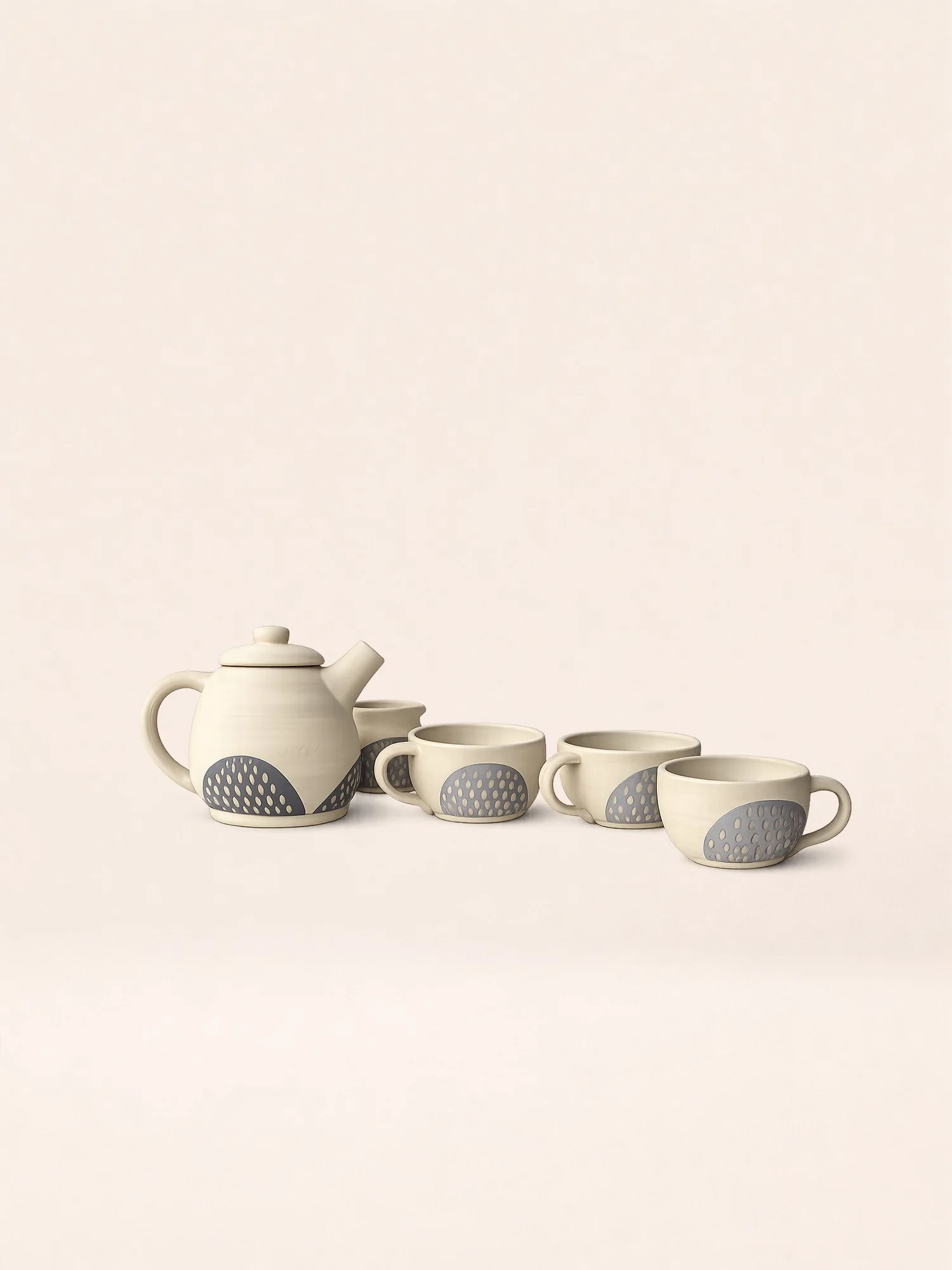 A set of four white ceramic cups and a teapot with gray decorative patterns, arranged in a line on a beige background.
