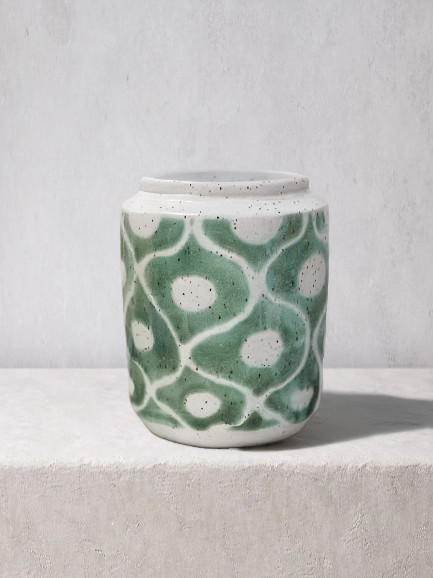 Handmade ceramic jar featuring a white clay body with a soft green organic pattern and subtle speckling.
