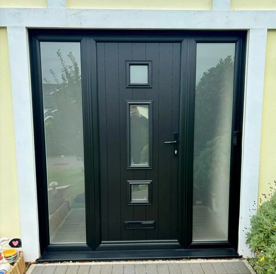 Black front door with three rectangular glass panels and side glass panels on either side, surrounded by white trim.