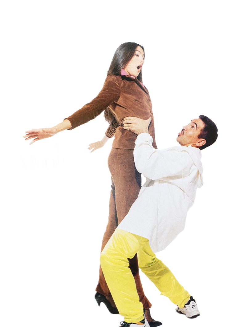 A woman in brown pants and a matching brown top appears to be performing a dance move, supported by a man in a white hoodie and yellow pants, who is holding her around the waist.