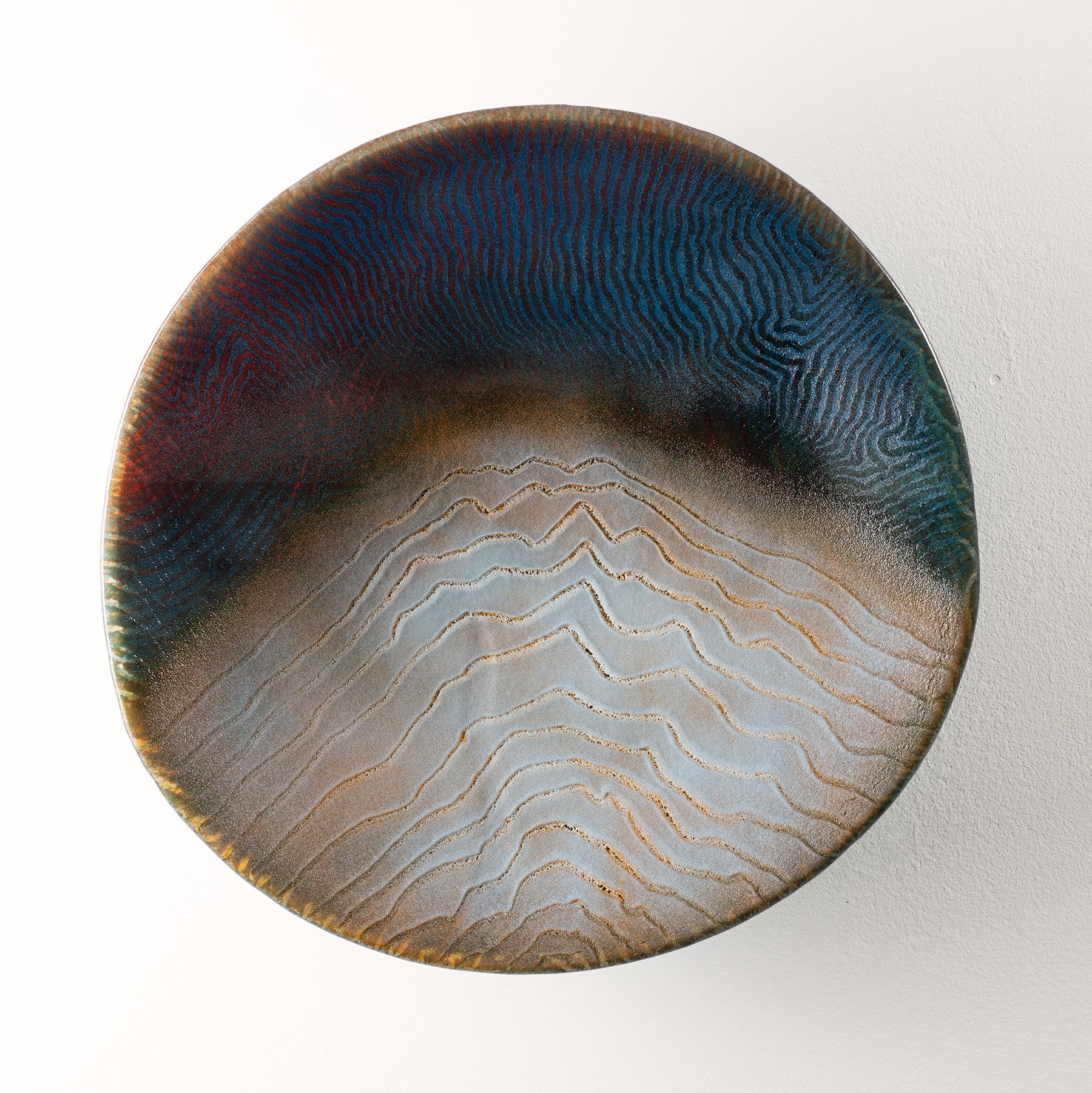 Decorative glass bowl with colorful abstract design and textured pattern, placed against a white background.