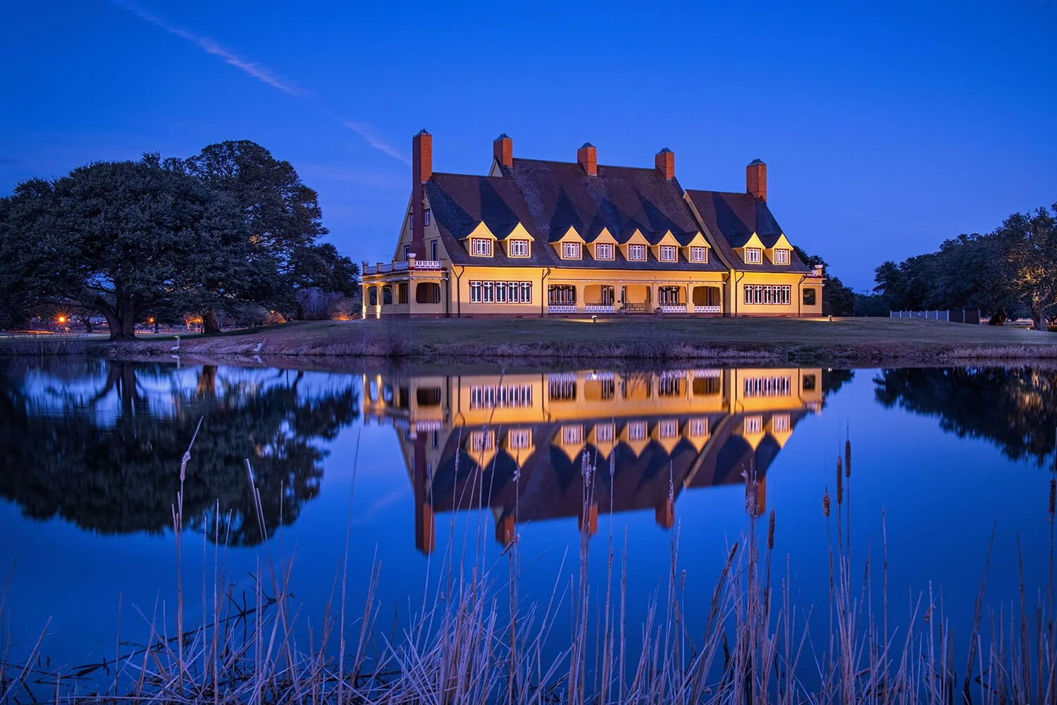 The Whale Head Club, in Historic Corolla Park on the Northern Outer Banks at Blue Hour with its reflection visible in the pond in front of the building.
