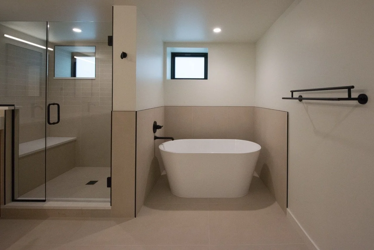 Custom downstairs bathroom shower and standalone tub surrounded by quality tile in Washington Park home remodel
