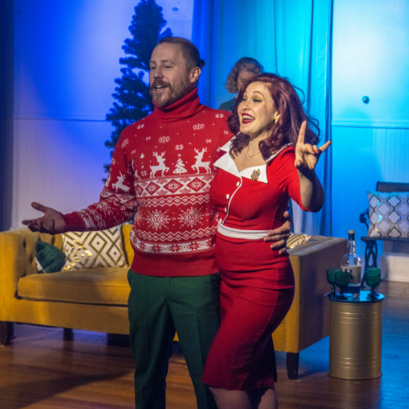 Two actors in a Christmas sweater and red dress in Christmas With the Rosses, an immersive theater show in Eureka Springs Arkansas, near Fayetteville, Bentonville, Springdale, and Rogers.
