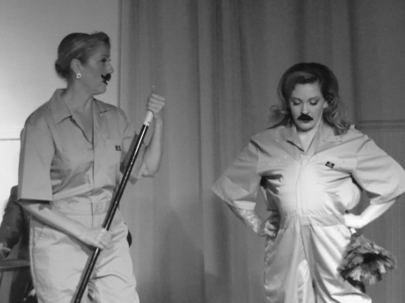 Two female actors comically dressed as men in Robbie, an immersive theater show in Eureka Springs Arkansas near Fayetteville, Bentonville, Rogers, and Springdale.