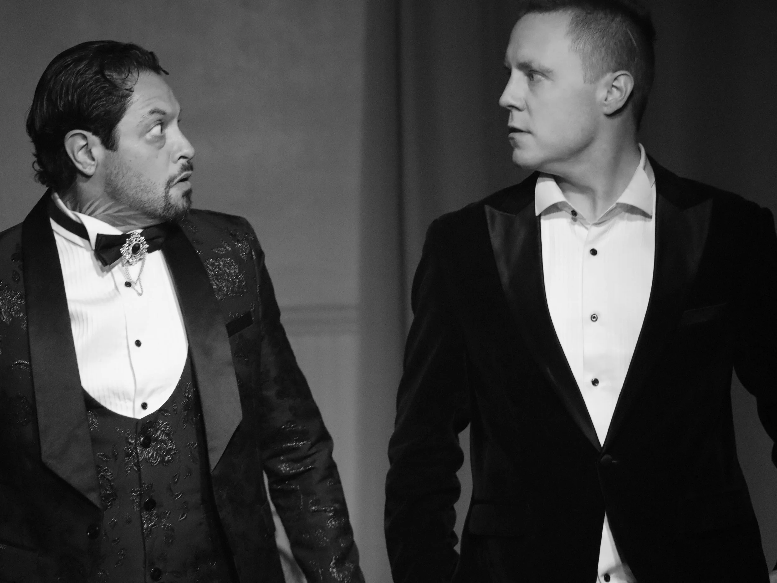 Two actors in formal suits look at each other intensely in ROBBIE, an immersive theater show in Eureka Springs Arkansas, near Bentonville, Rogers, Fayetteville, and Springdale.