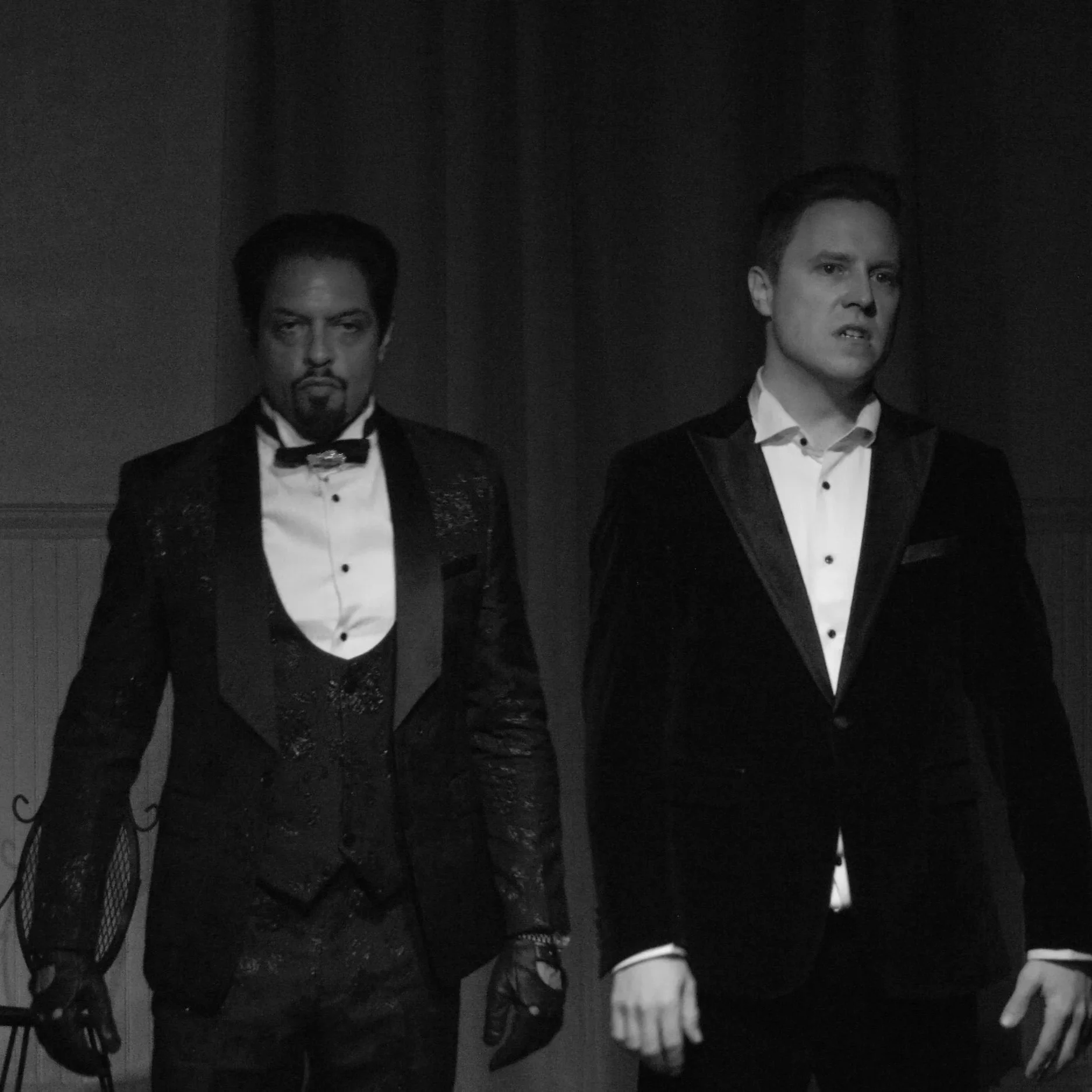 Two actors in black suits giving intimidating looks in ROBBIE, an immersive theater show in Eureka Springs Arkansas, near Fayetteville, Bentonville, Rogers, and Springdale.