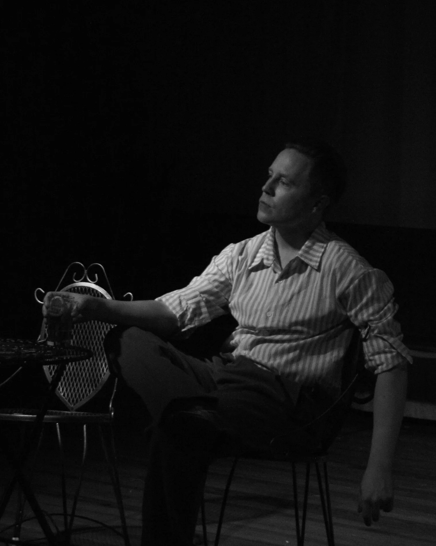 Actor in striped shirt sitting with a cup of espresso in Robbie, an immersive theater show in Eureka Springs Arkansas near Bentonville, Fayetteville, Springdale, and Rogers.