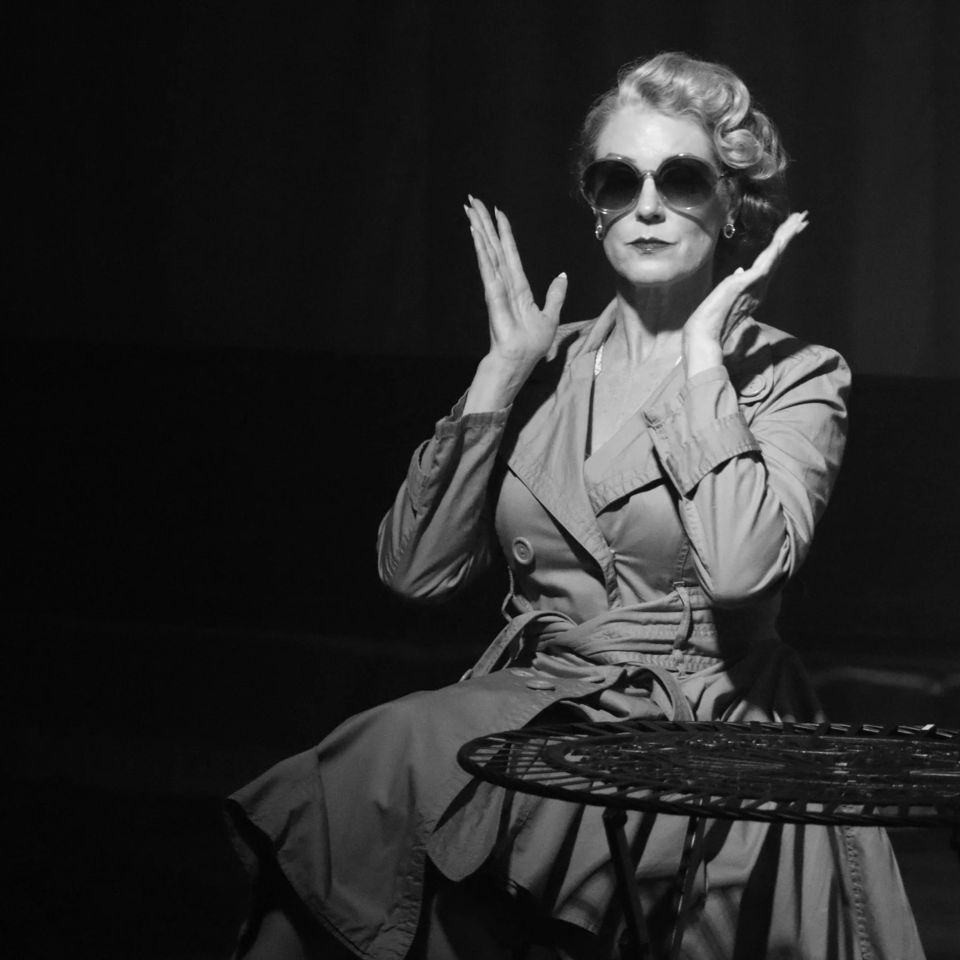 A mysterious woman in a trenchcoat and sunglasses in ROBBIE, an immersive theater show in Eureka Springs Arkansas, near Fayetteville, Bentonville, Rogers, and Springdale.