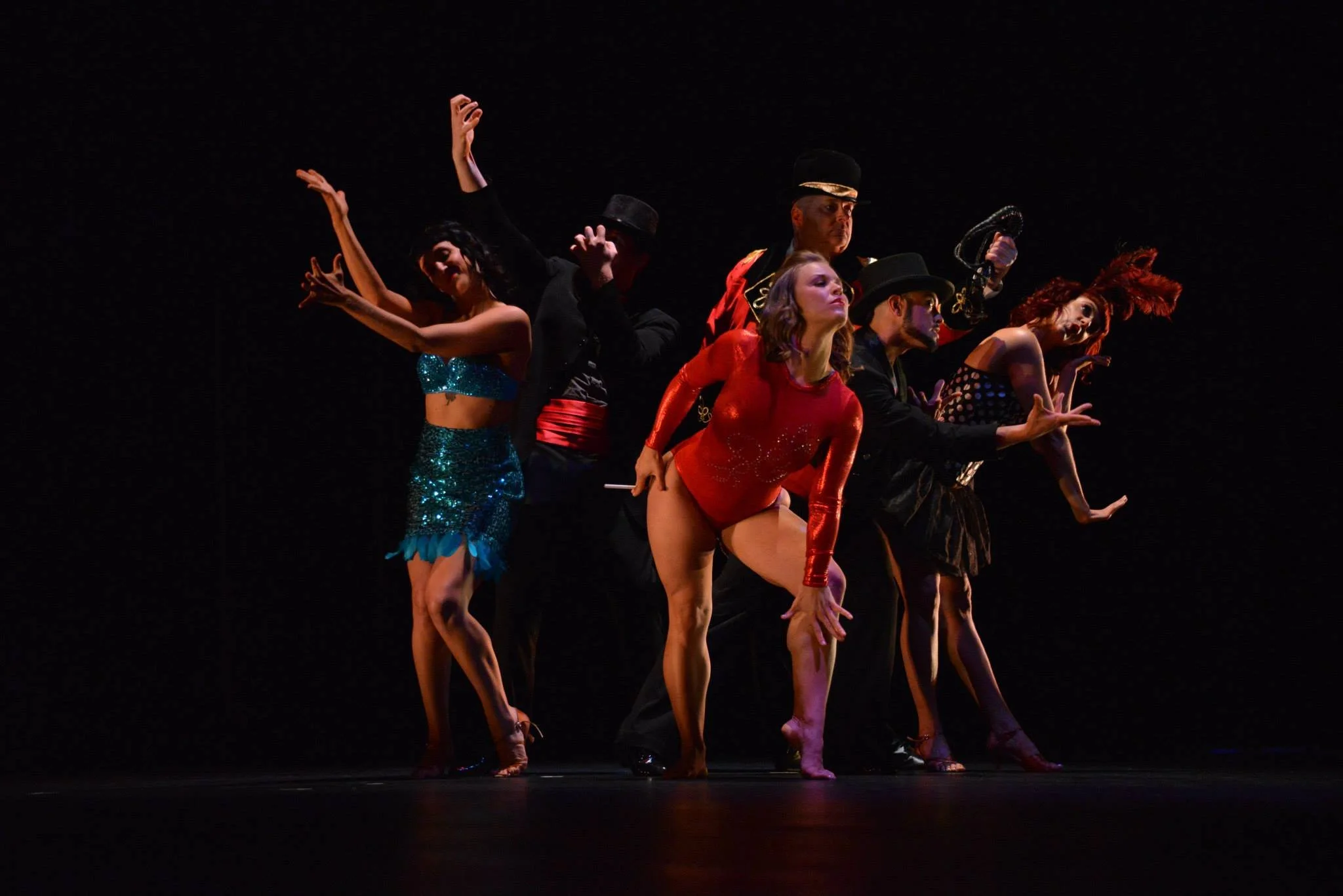 Dancers on a stage strike various poses in circus style costumes for The Night Circus, an early production of the Melonlight Theater.