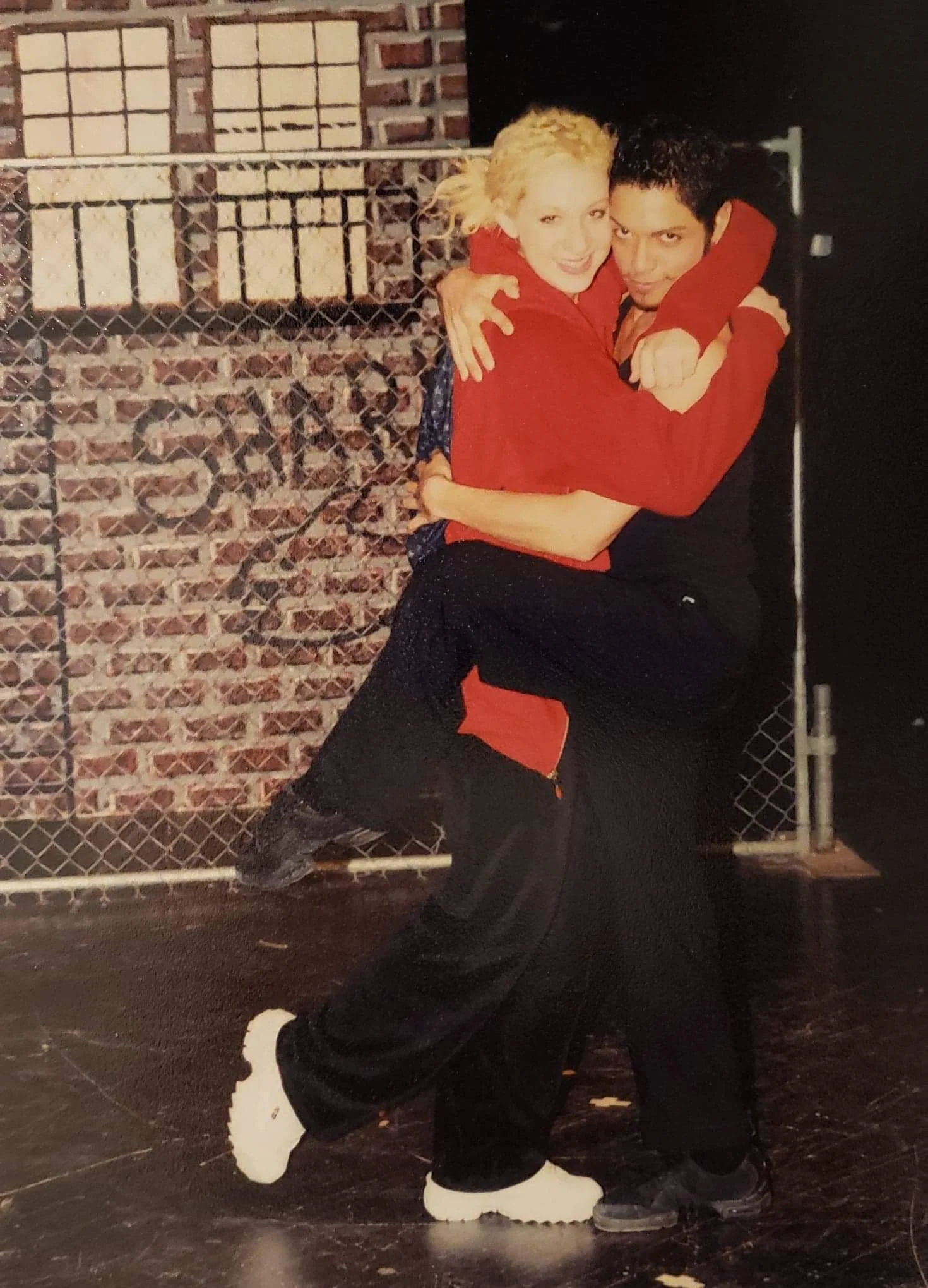 Emily and Raymond share a dancey and affectionate embrace on their high school stage.