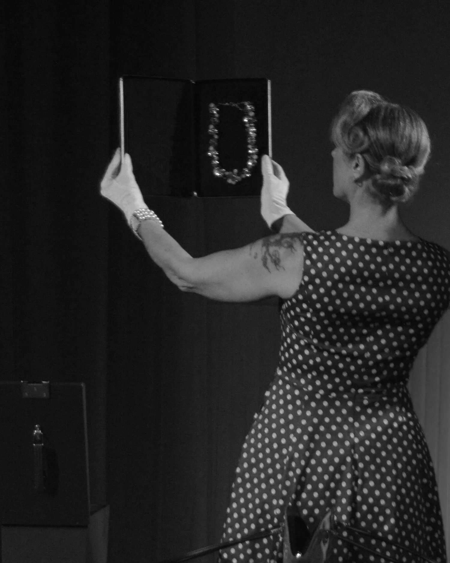 Actor wearing gloves and holding expensive jewelry in Robbie, an immersive THEATER show in Eureka Springs Arkansas near Bentonville, Fayetteville, Rogers, and Springdale.