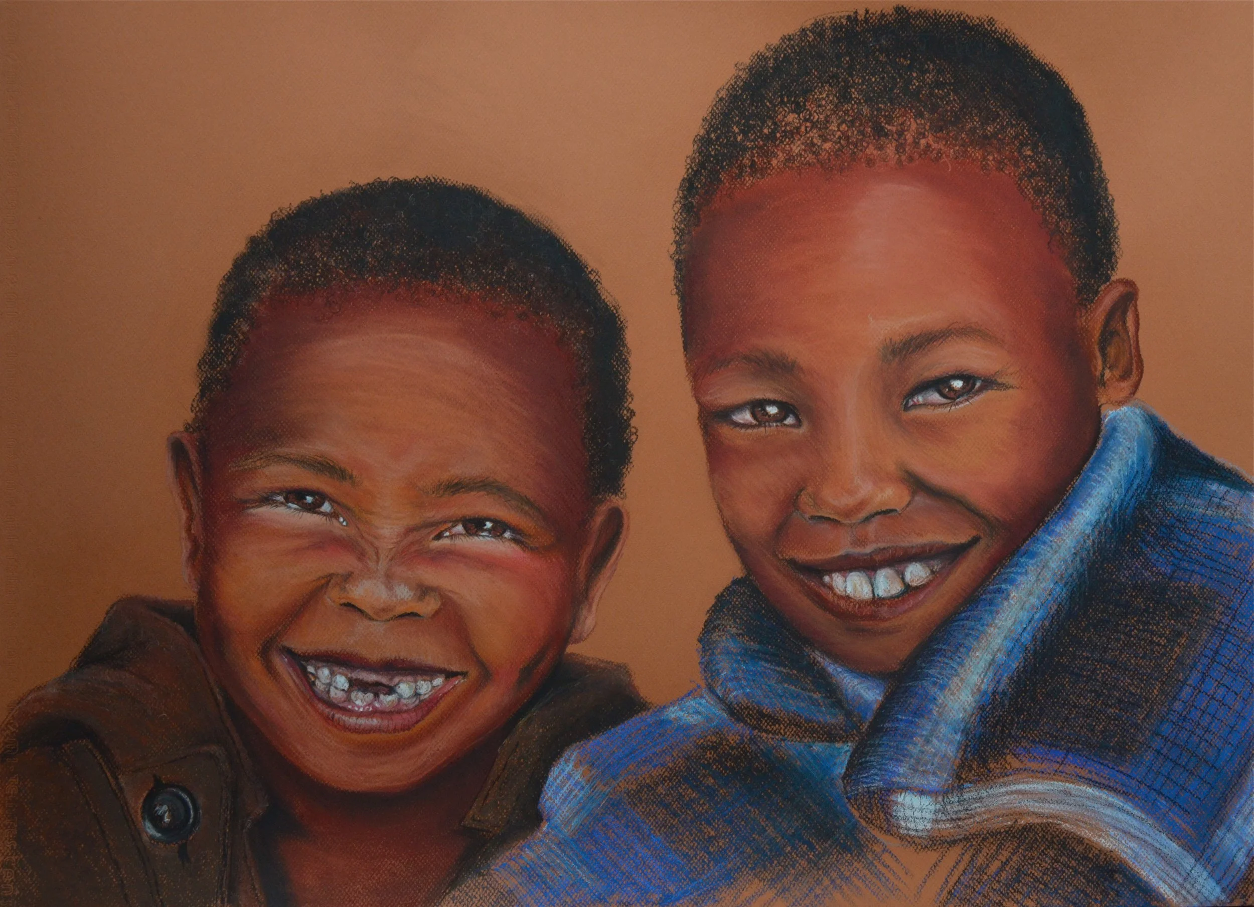 Photograph of two young boys smiling and showing their teeth, with the boy on the left having a big grin and the boy on the right smiling warmly, dressed in a blue checked shirt and a brown jacket, against a plain brown background.