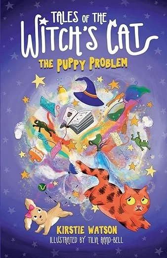 Book cover titled 'Tales of the Witch's Cat: The Puppy Problem' by Kirstie Watson, illustrated by Tila Randall-Bell, featuring a wide-eyed orange tabby cat, a small dog, a wizard hat, a magic wand, a book, a feather, and various stars and sparkles ag