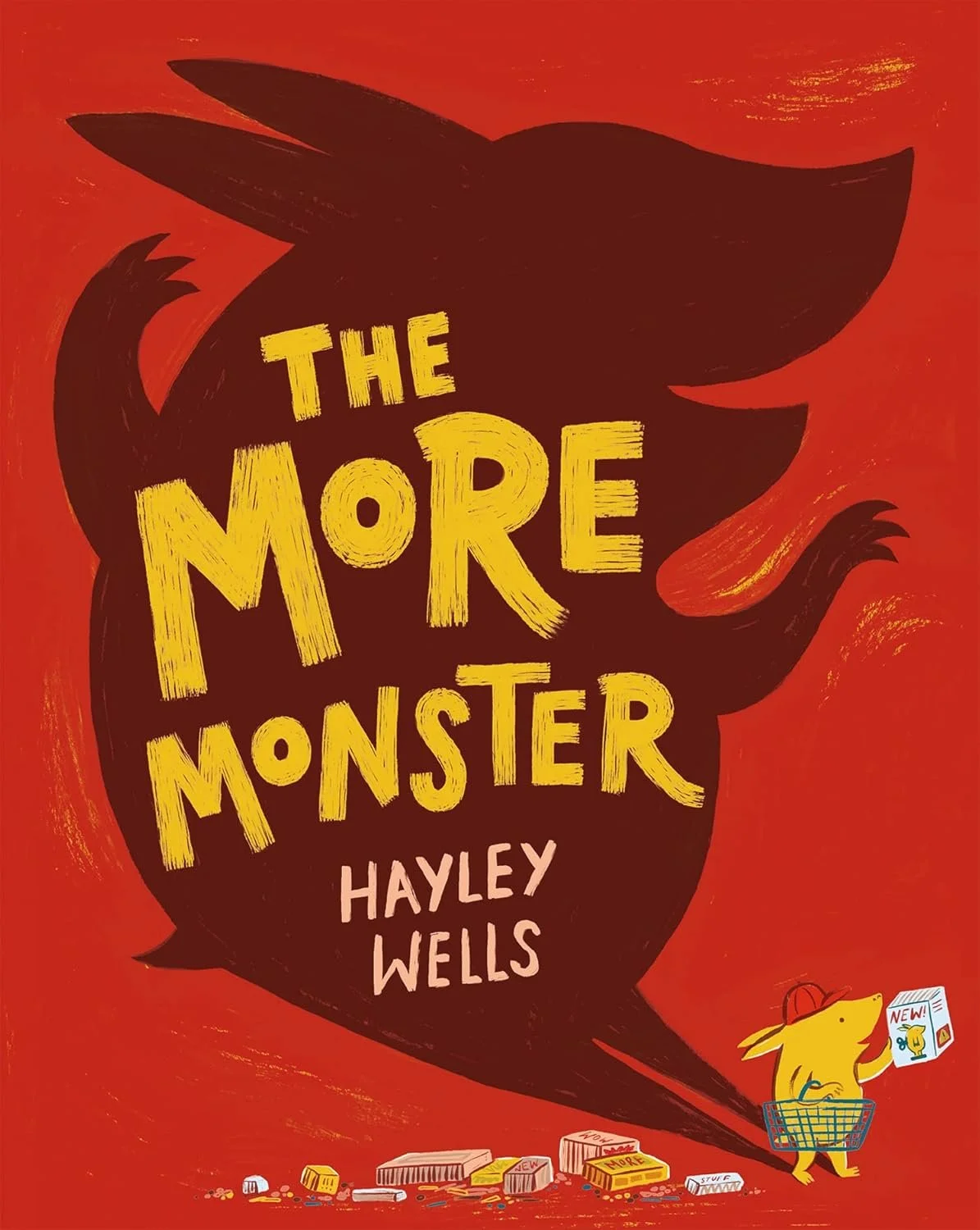 Book cover titled "The More Monster" by Hayley Wells, featuring a yellow monster shopping for candy at a grocery store, with scattered candy wrappers and a shopping basket.