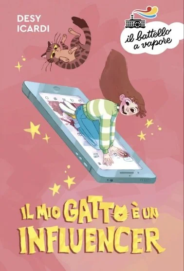 A girl with long hair is crawling on a large smartphone, with a cat floating above her. The background is pink with yellow stars. There is a speech bubble with Italian text and a small illustration of a boat. The text on the image says 'Il mio gatto 