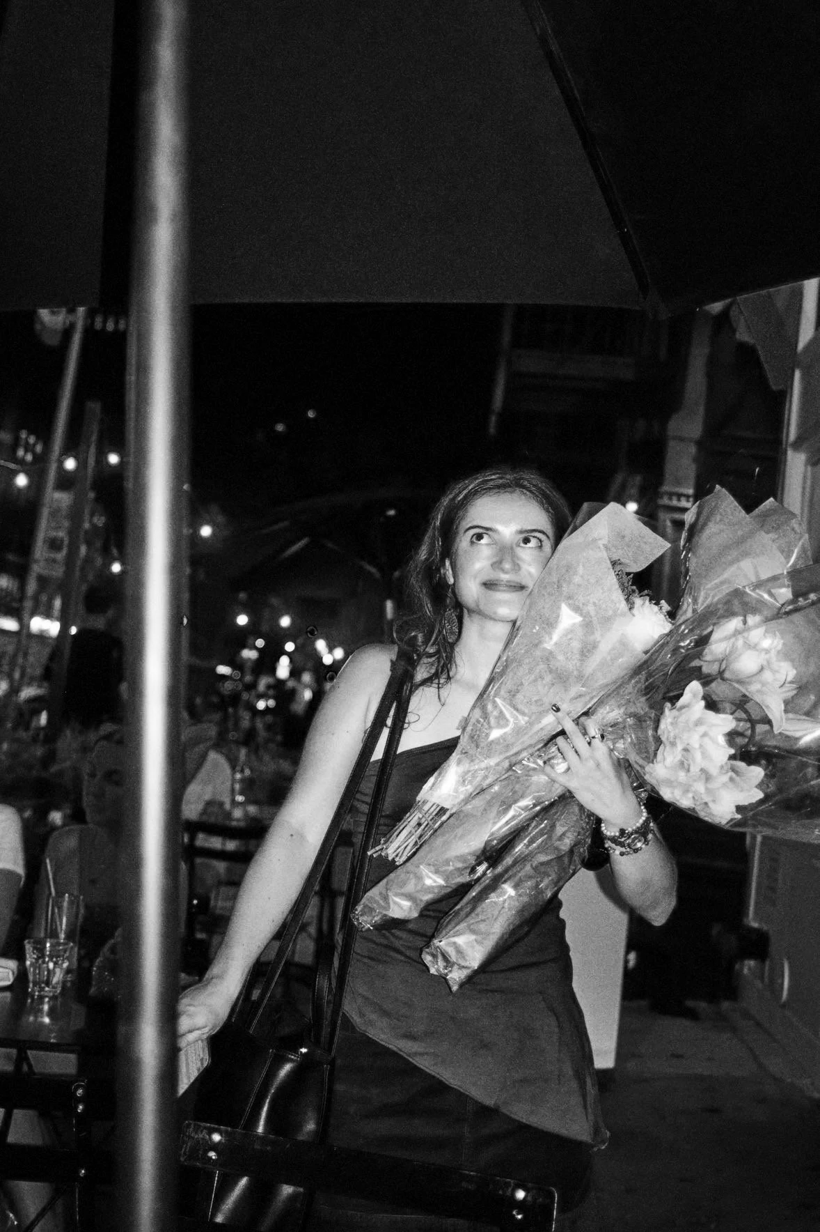 A woman holding multiple bouquets of flowers at an outdoor night setting.