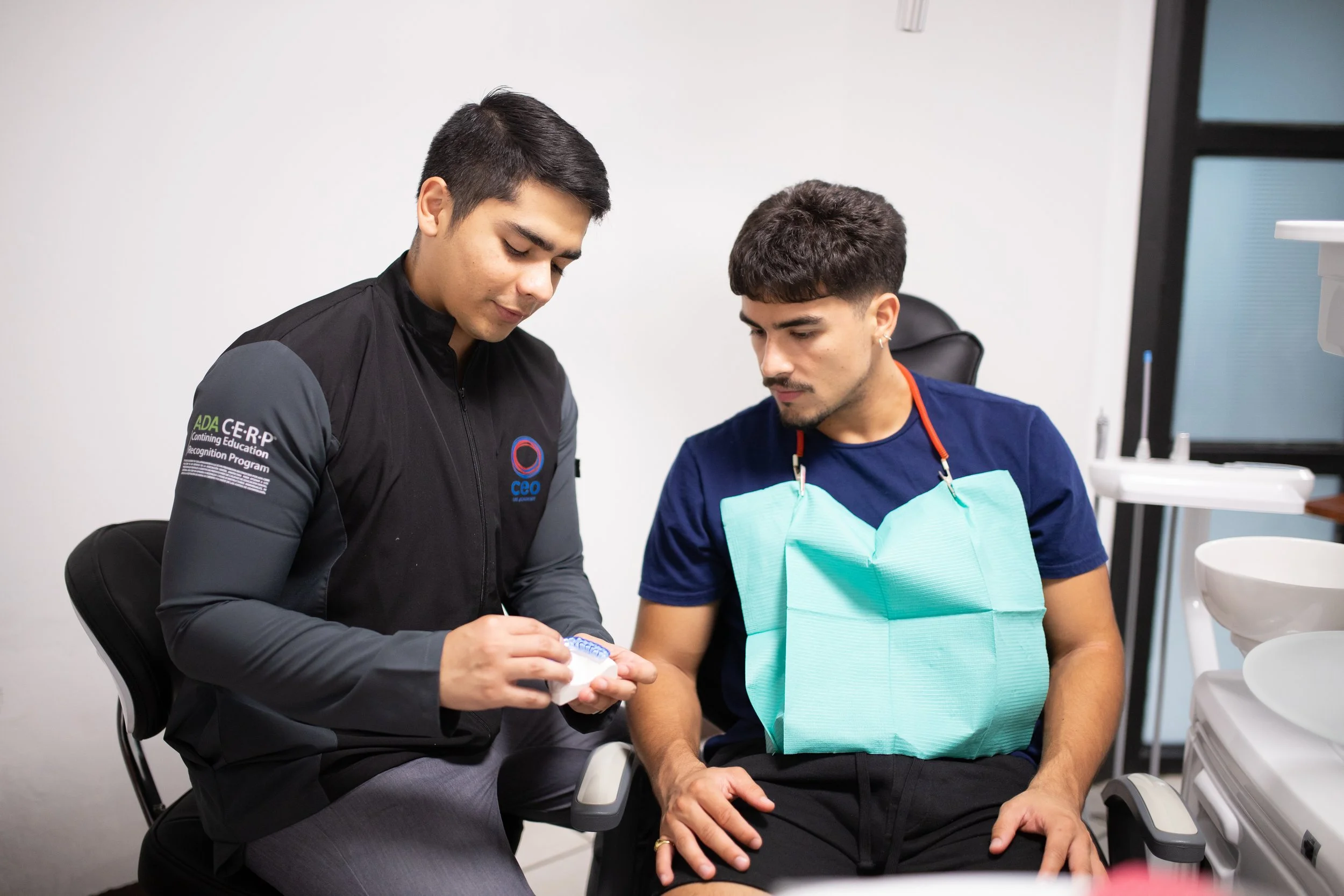 Dental professional showing dental impression to patient in dental office.