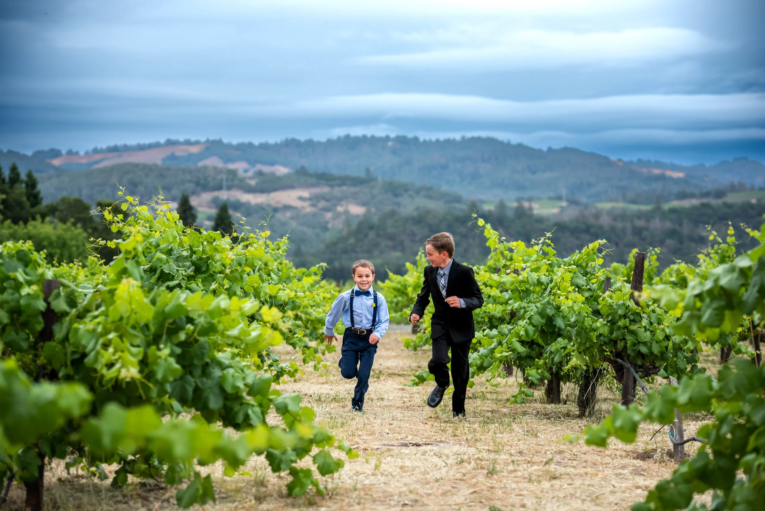 ring bearers running through vineyard