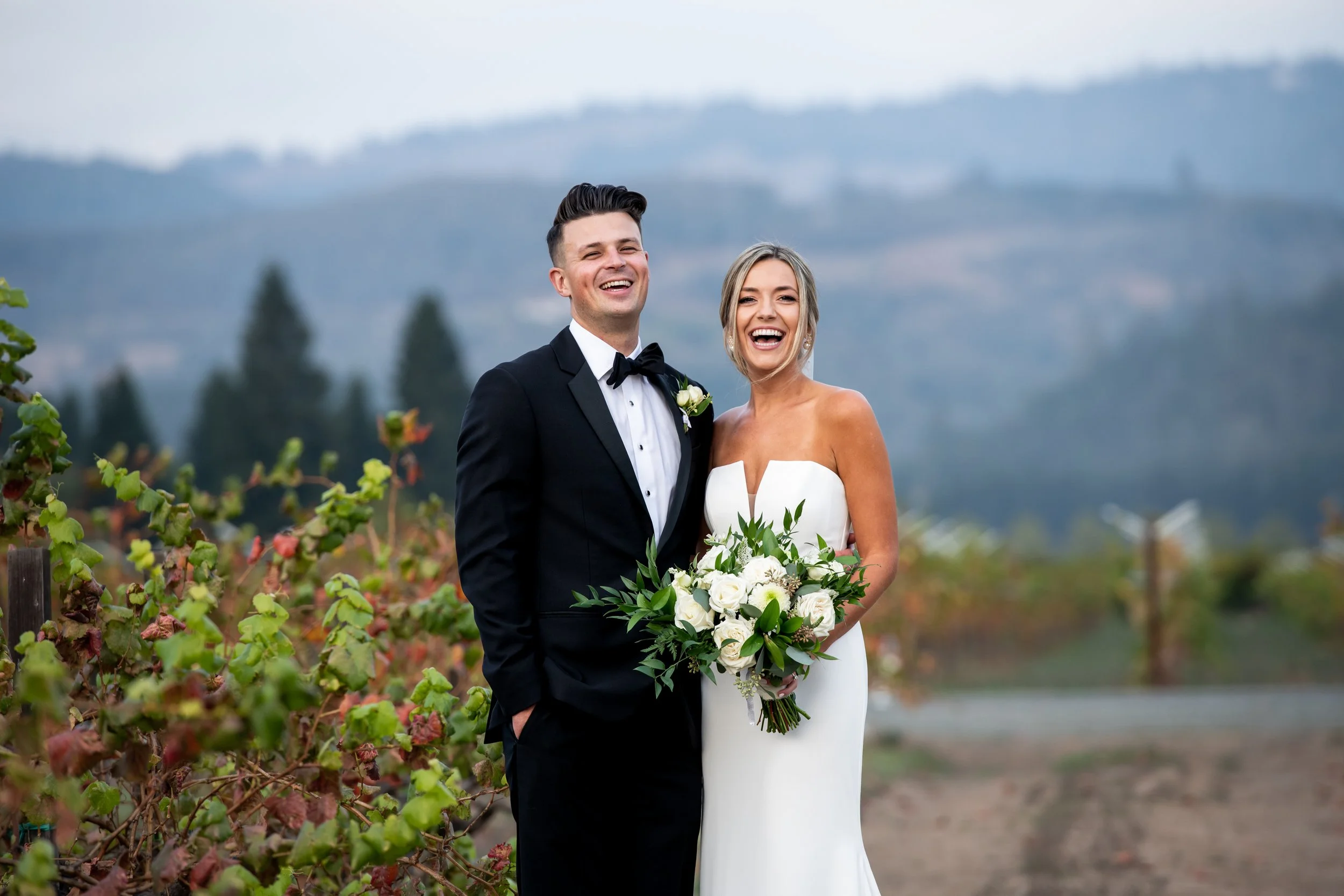 Bride and groom laughing in vineyard