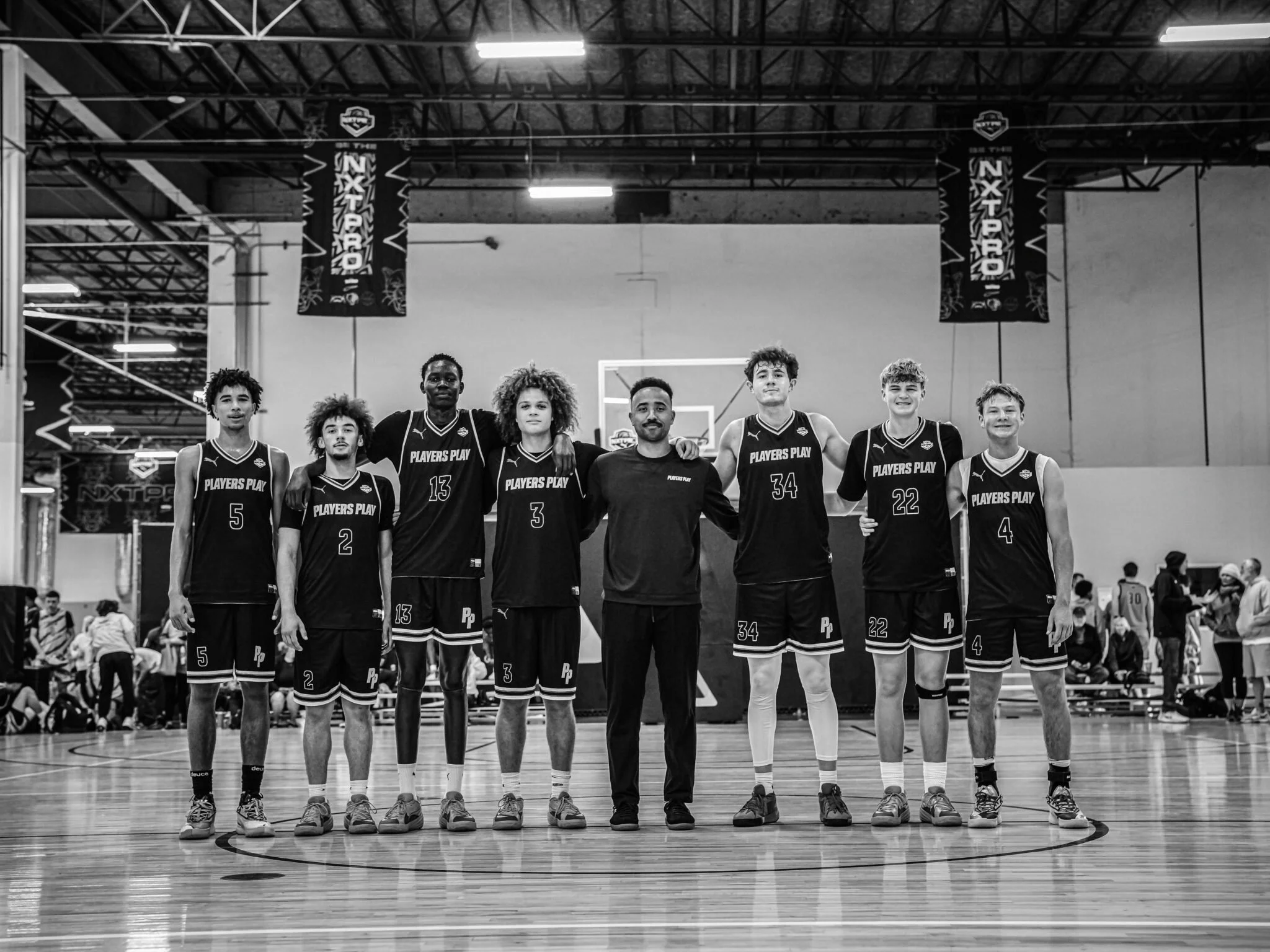 A basketball team with six players and a coach standing together on an indoor court, posing for a team photo.