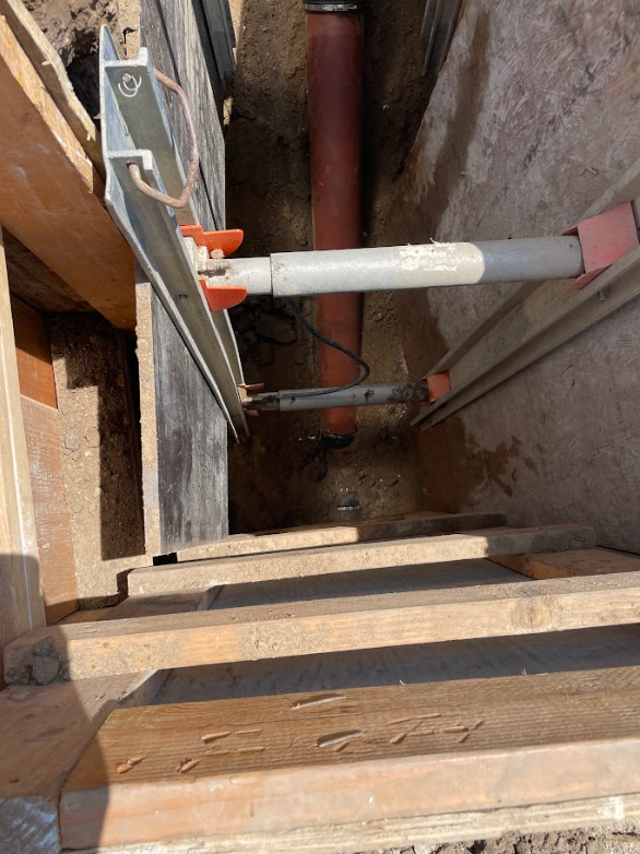 View of a construction site showing exposed underground plumbing pipes and wooden framing.