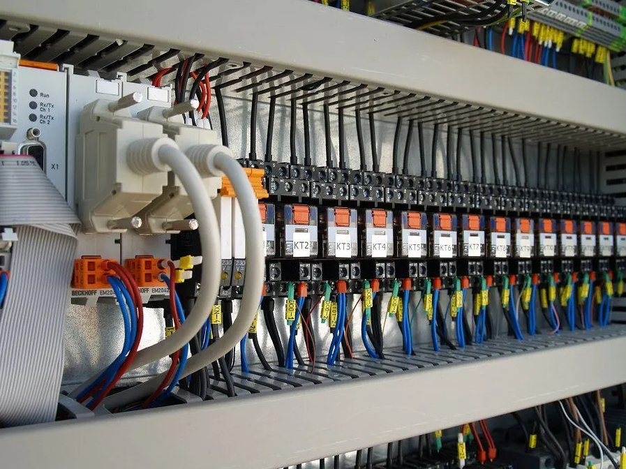Electrical control panel with wires, relays, terminal blocks, and circuit breakers.