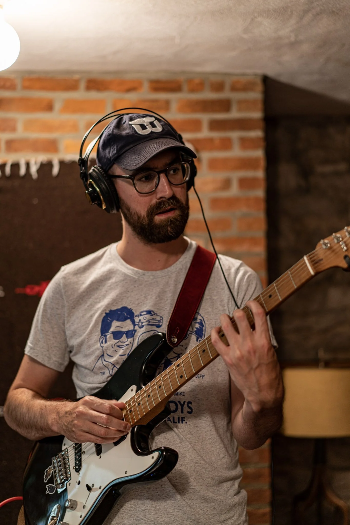A guitarist playing guitar, wearing headphones during the Esteban recording session.