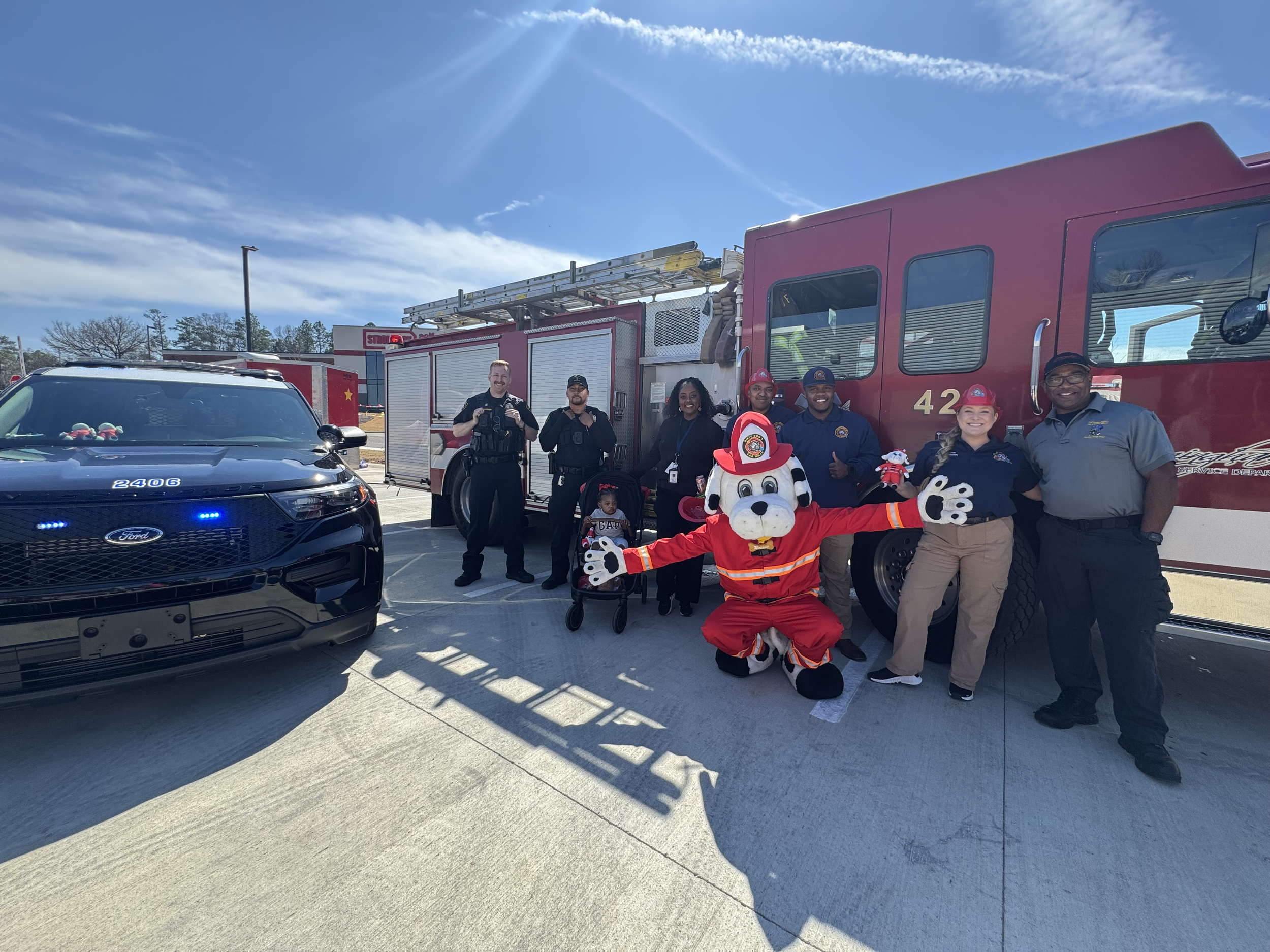 The Birmingham local hero community with the Dirty Dog's Car Wash team and mascot in front of police service vehicle and fire truck on the day of Grand Opening.