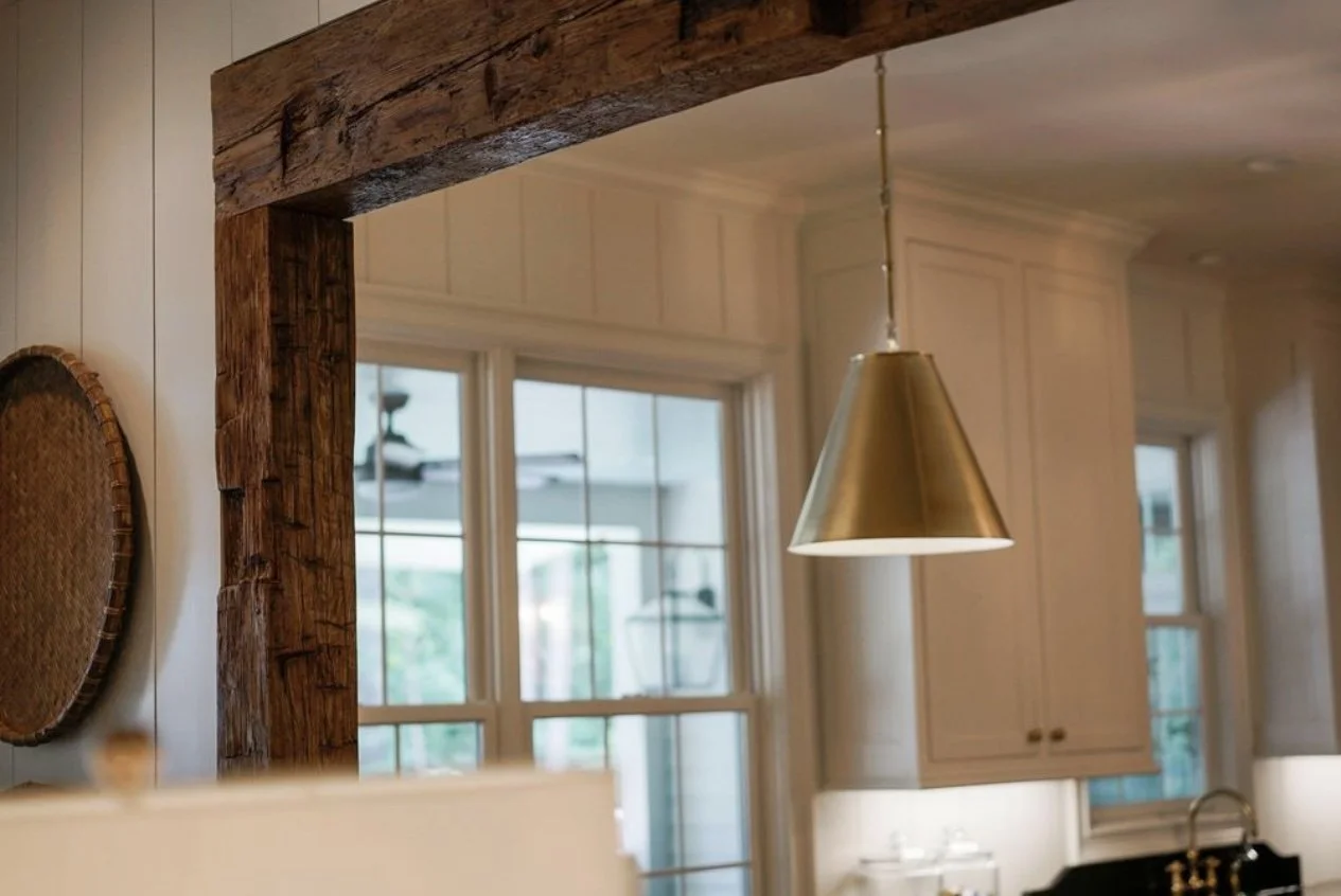 Interior view of a kitchen with white cabinetry, large window, and a metallic pendant light.
