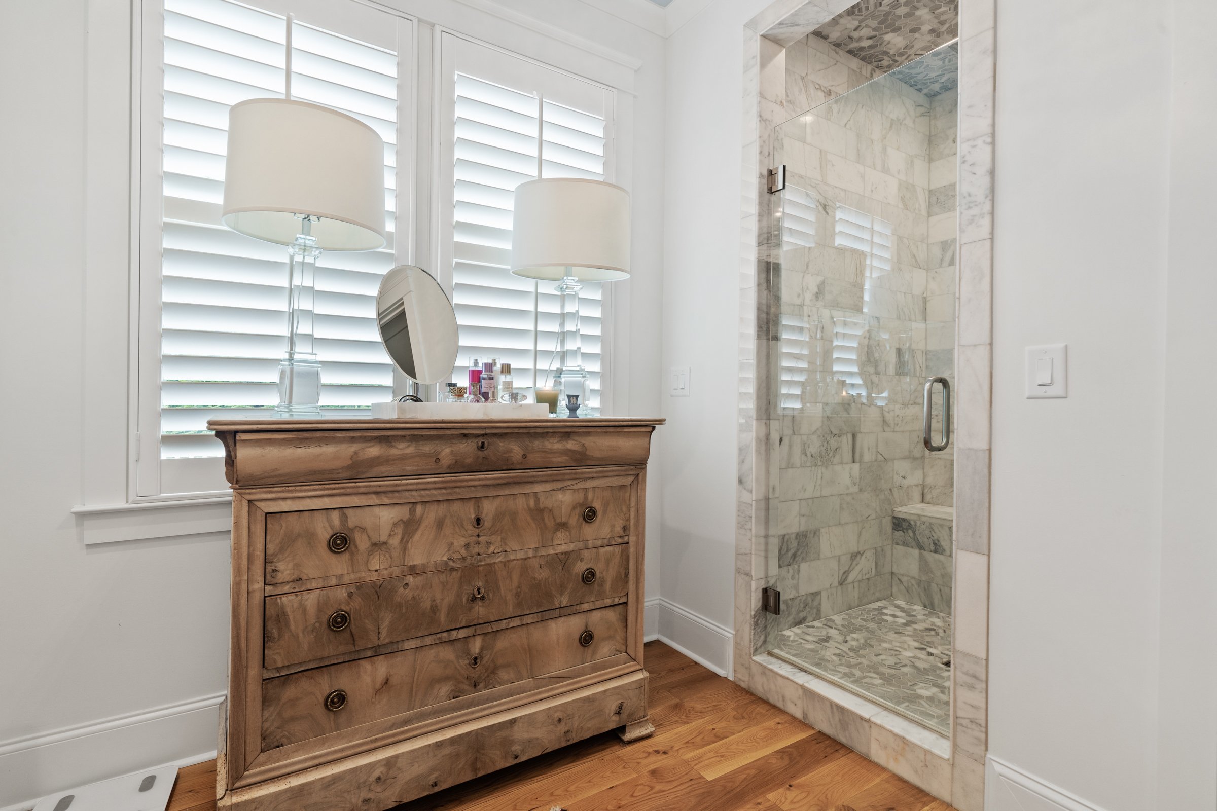 Walk-in standing marble shower with wooden dresser