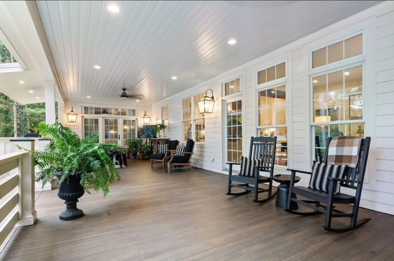 Spacious screened porch with rocking chairs, potted plants, and large windows
