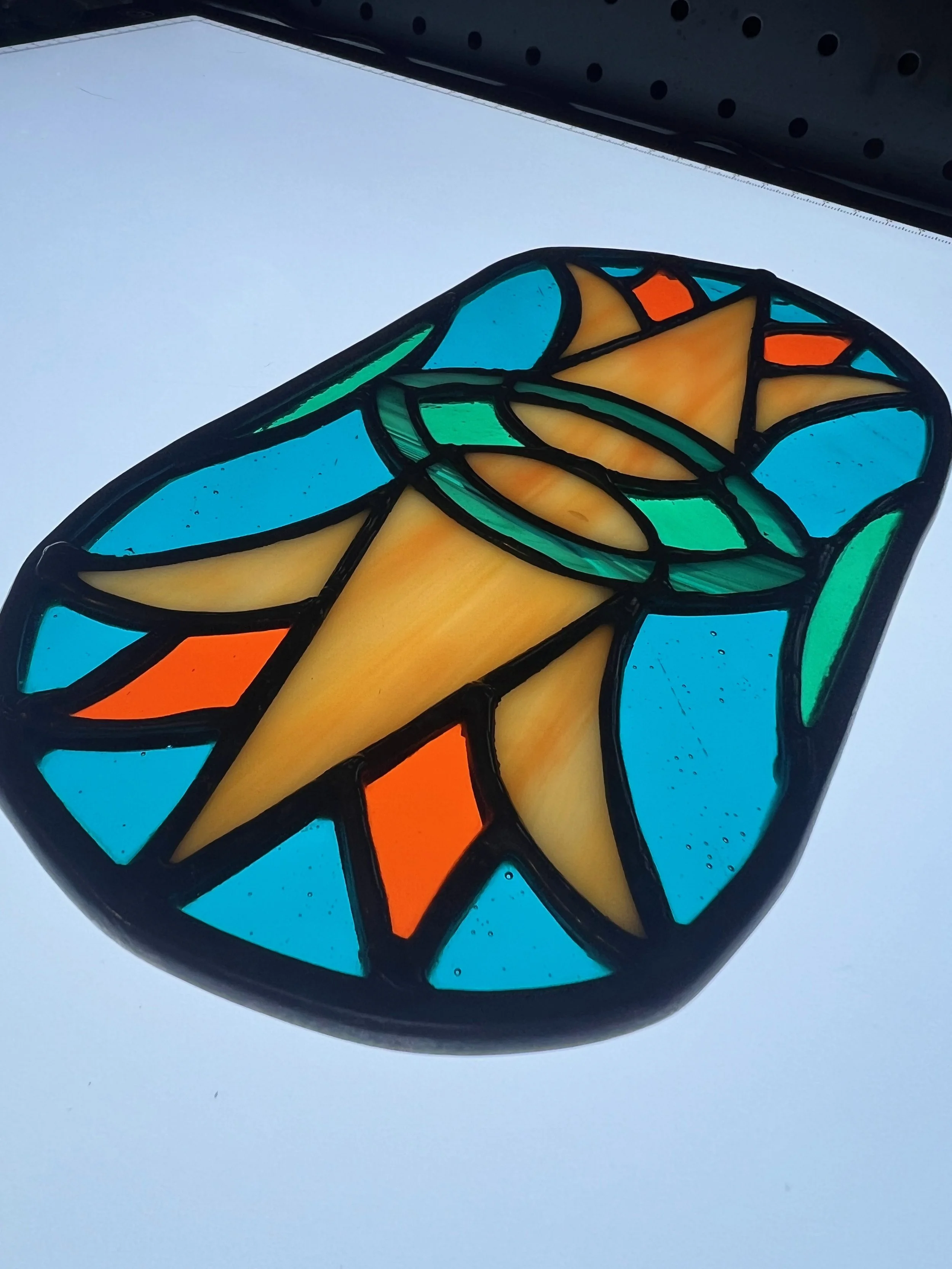 Colorful stained glass butterfly with blue, yellow, orange, and green segments outlined in black.