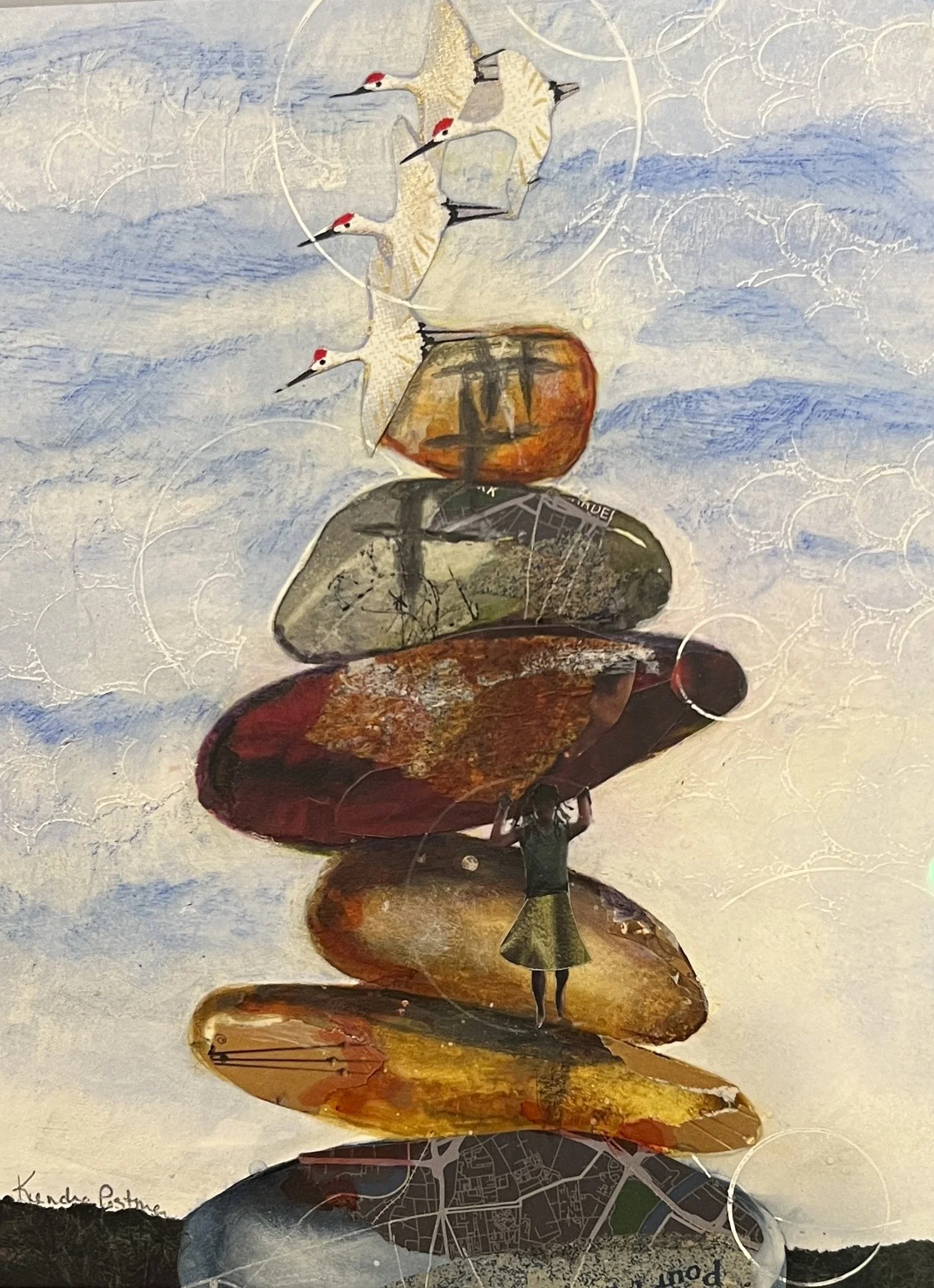 A mixed media artwork depicting a woman stacking large, colorful rocks, with a background of sky and clouds. Three white birds with red crowns fly above the rocks.