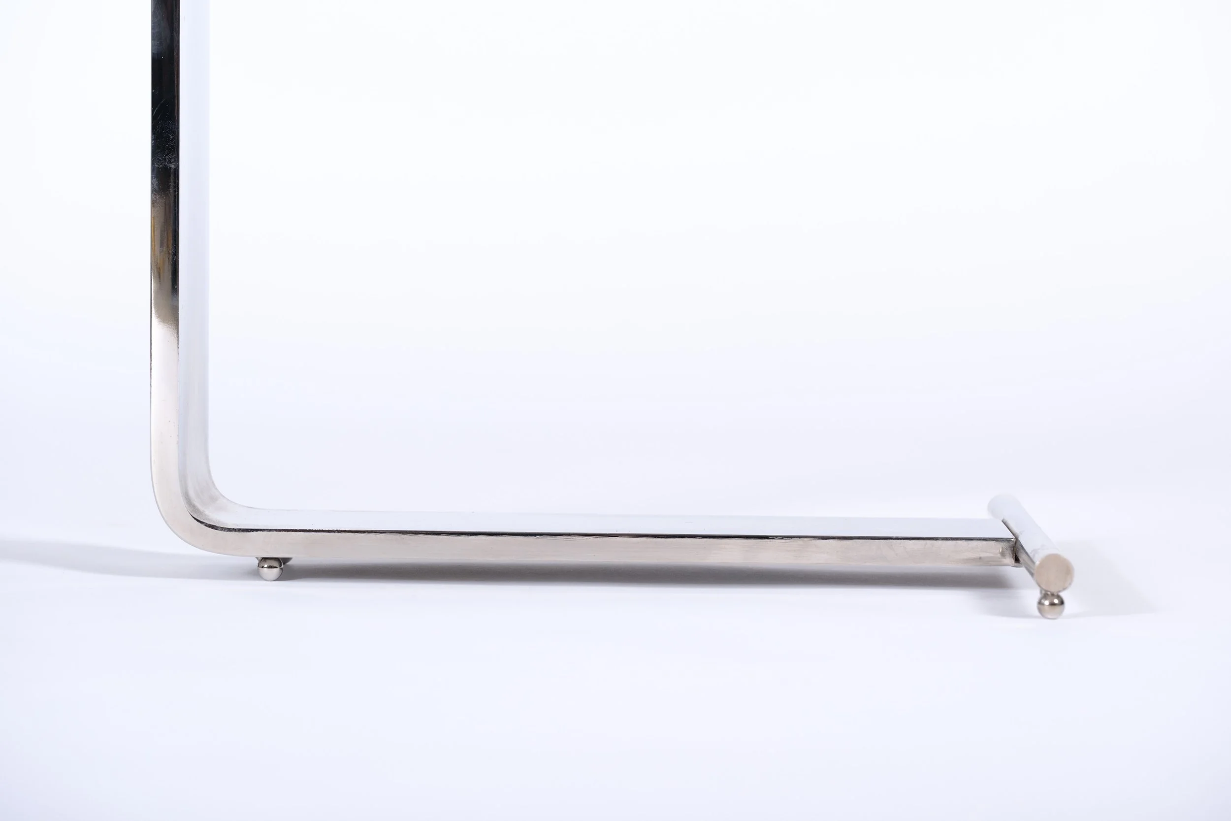 c-shaped side table with glass tabletop and nickel leg and base, close up leg and base