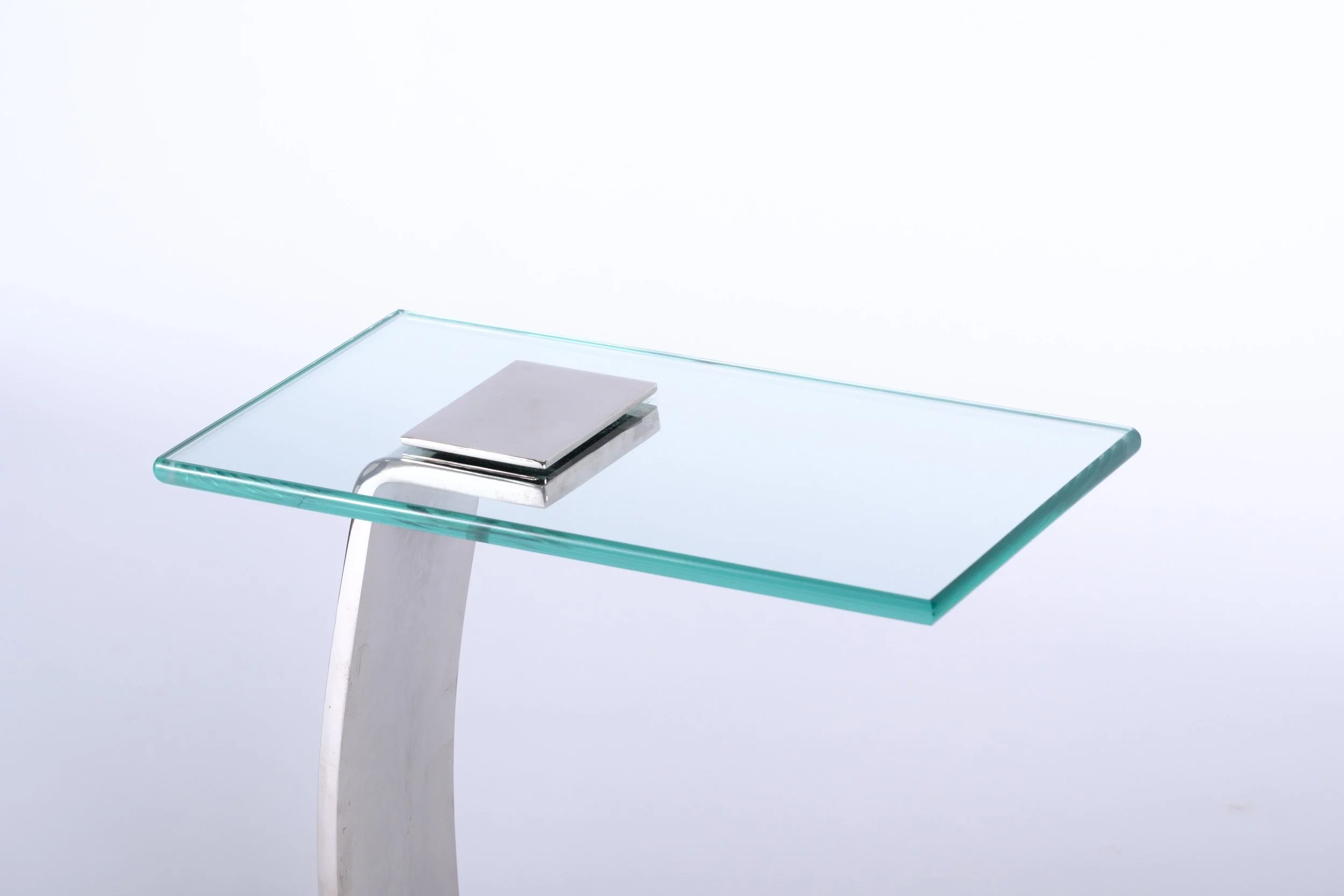 c-shaped side table with glass tabletop and nickel leg and base, close up corner