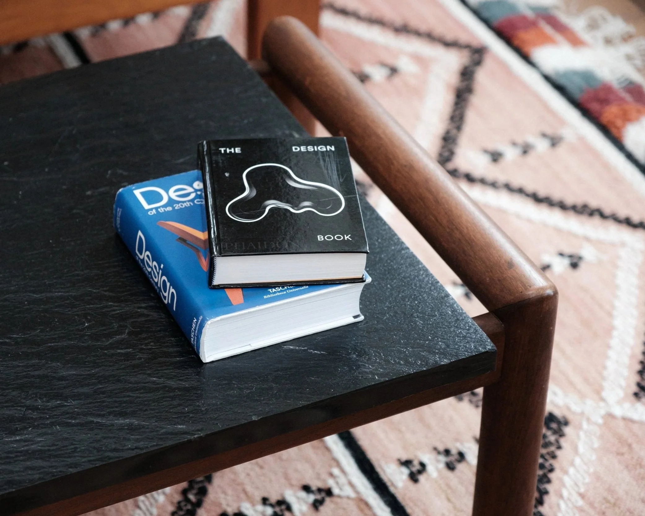 two design books sitting on top of black and brown mid-century modern wooden coffee table