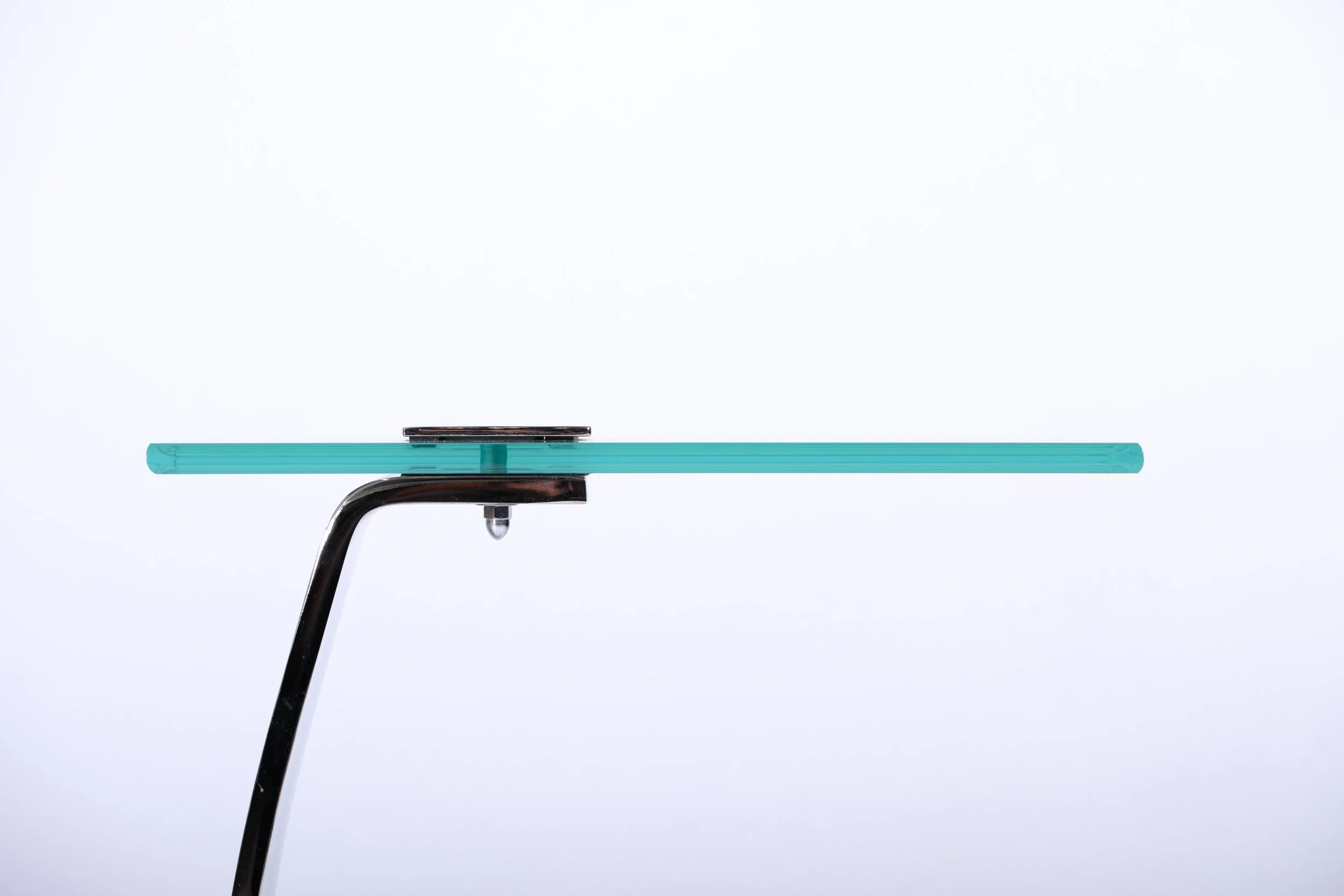 c-shaped side table with glass tabletop and nickel leg and base, close up side