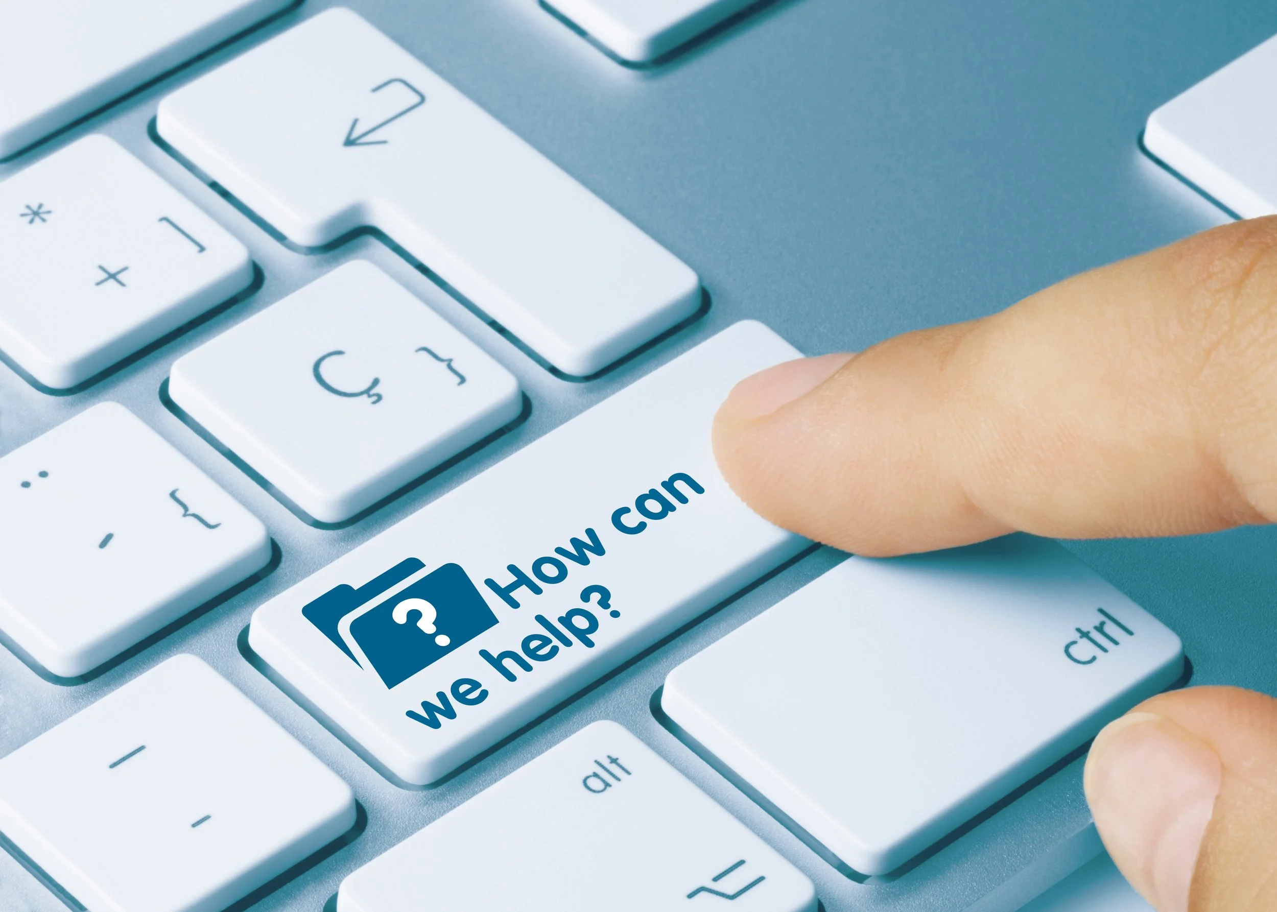 Close-up of a computer keyboard with a finger pressing a key that has a sticker on it reading 'How can we help?' with an icon of a speech bubble and a question mark.