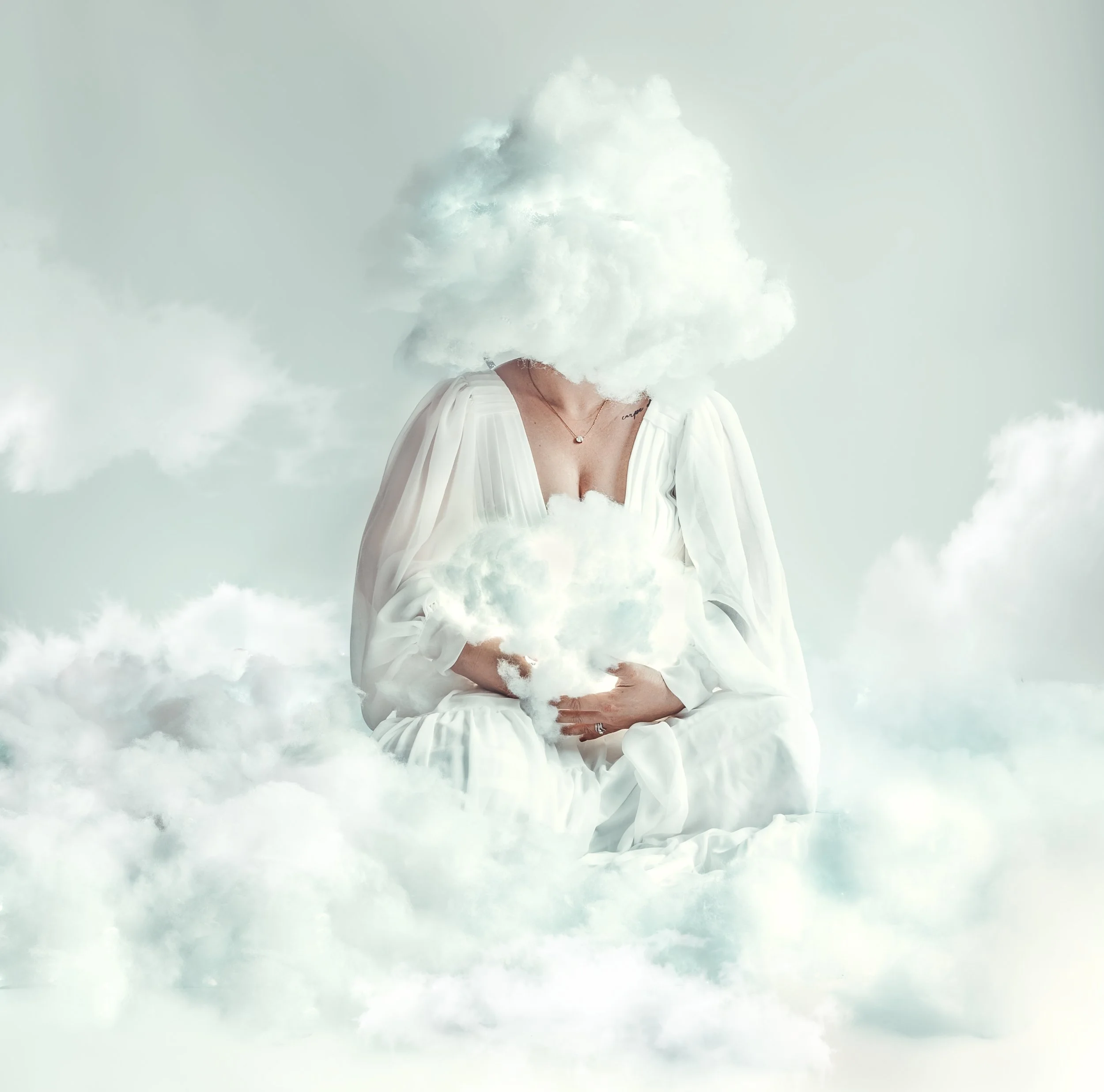 A person dressed in a white gown sitting on clouds with a cloud covering their face, holding a cloud in their hands.