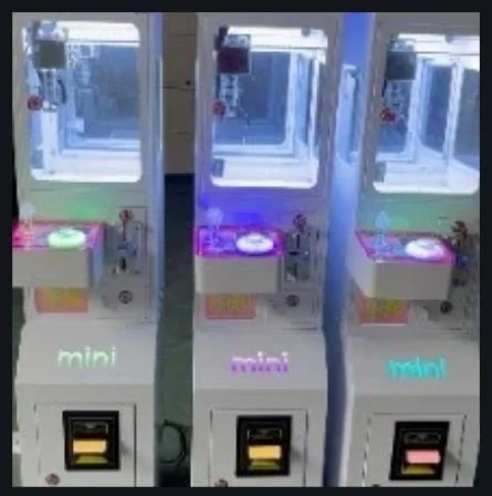 Three claw machines with colorful lights and plush toys inside.