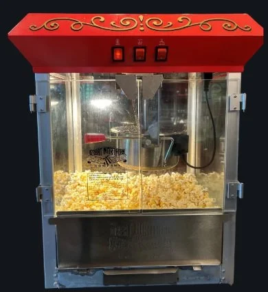 A popcorn machine with red decorative top filled with freshly popped popcorn.